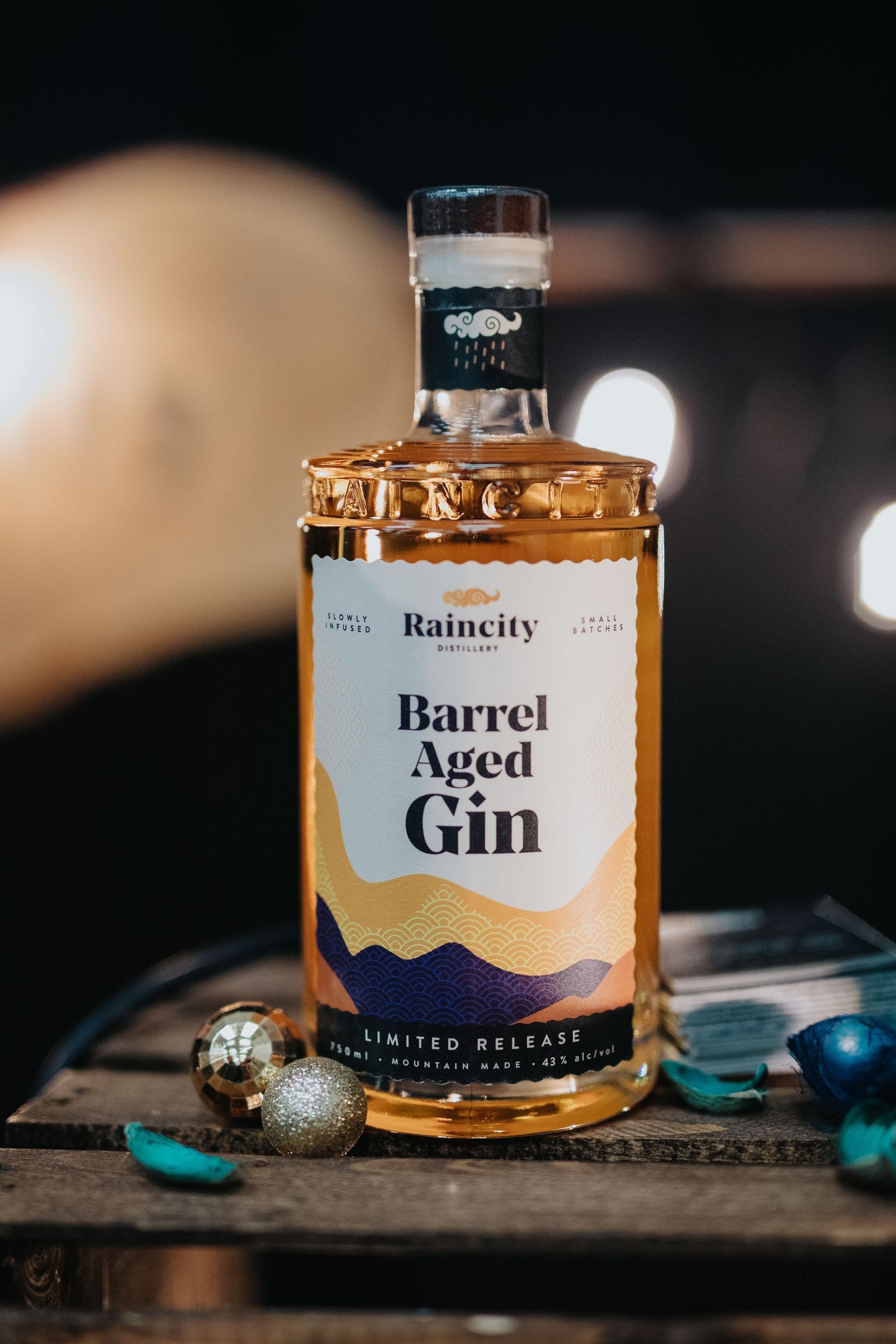 Artisanal barrel-aged gin bottles displayed with decorative holiday ornaments.