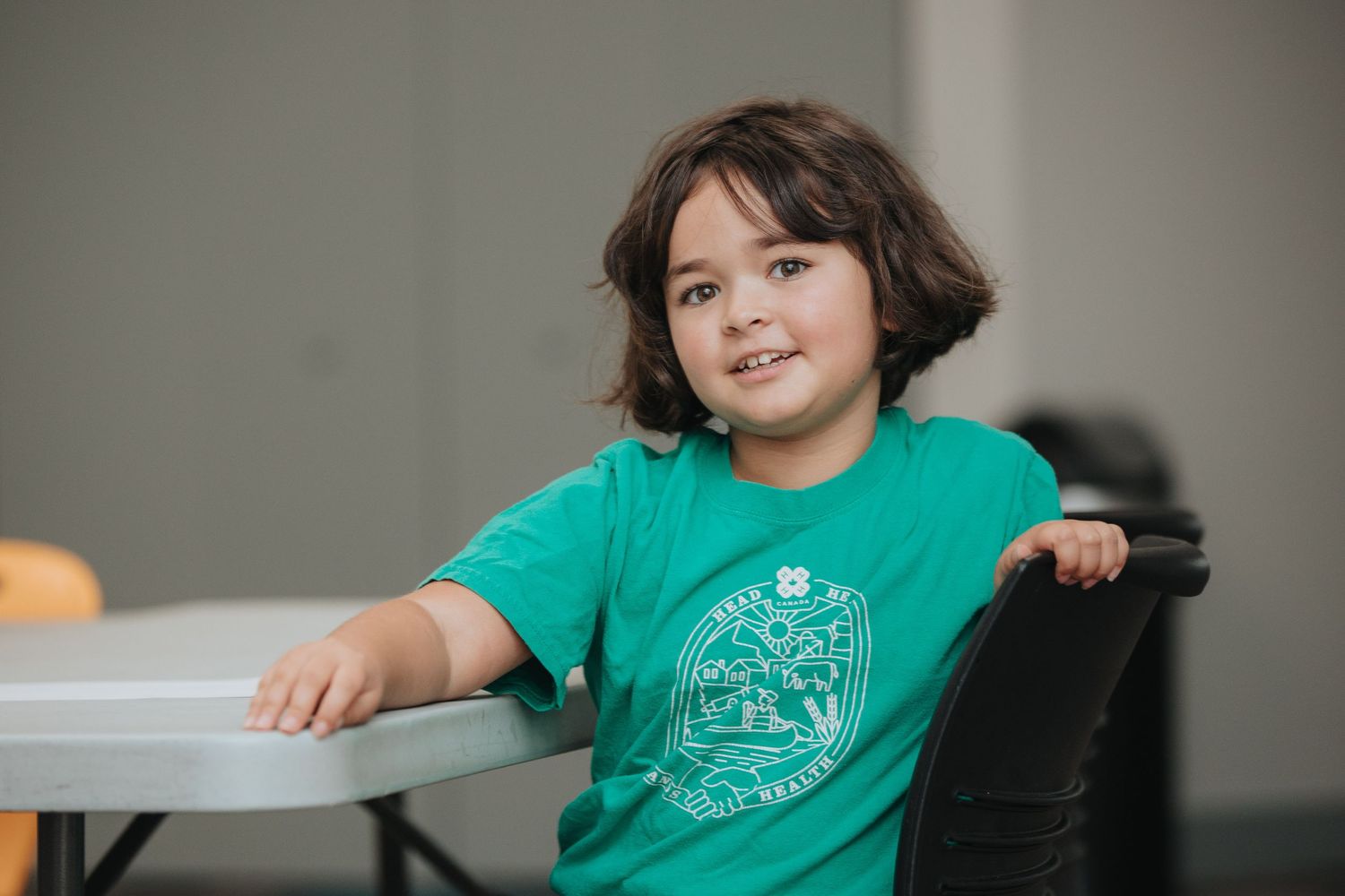 Person in teal shirt gestures while engaging with others in a library setting.