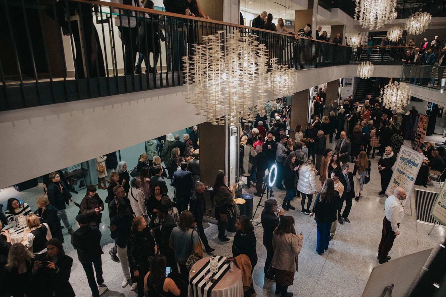 Large crowd mingling in an elegant indoor venue with high ceilings.
