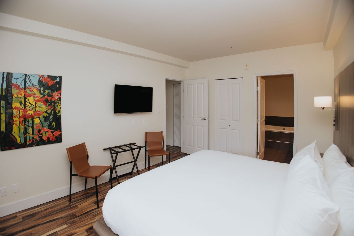 Clean and bright hotel room interior with white bedding and modern furnishings.