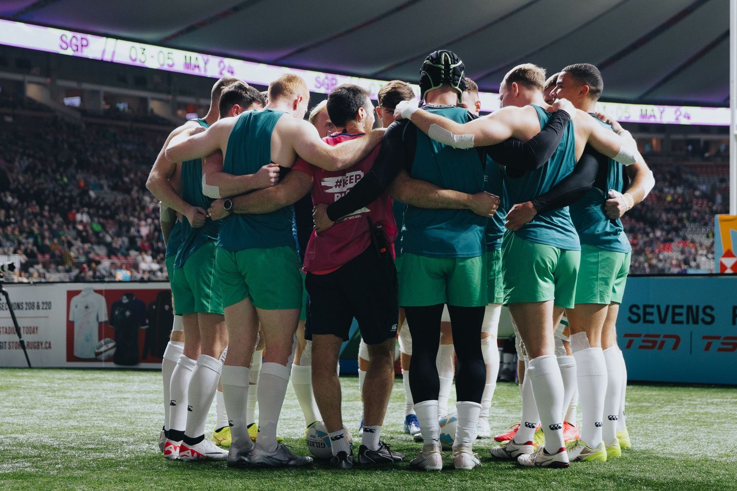 Rugby team huddles together on field during competitive match.
