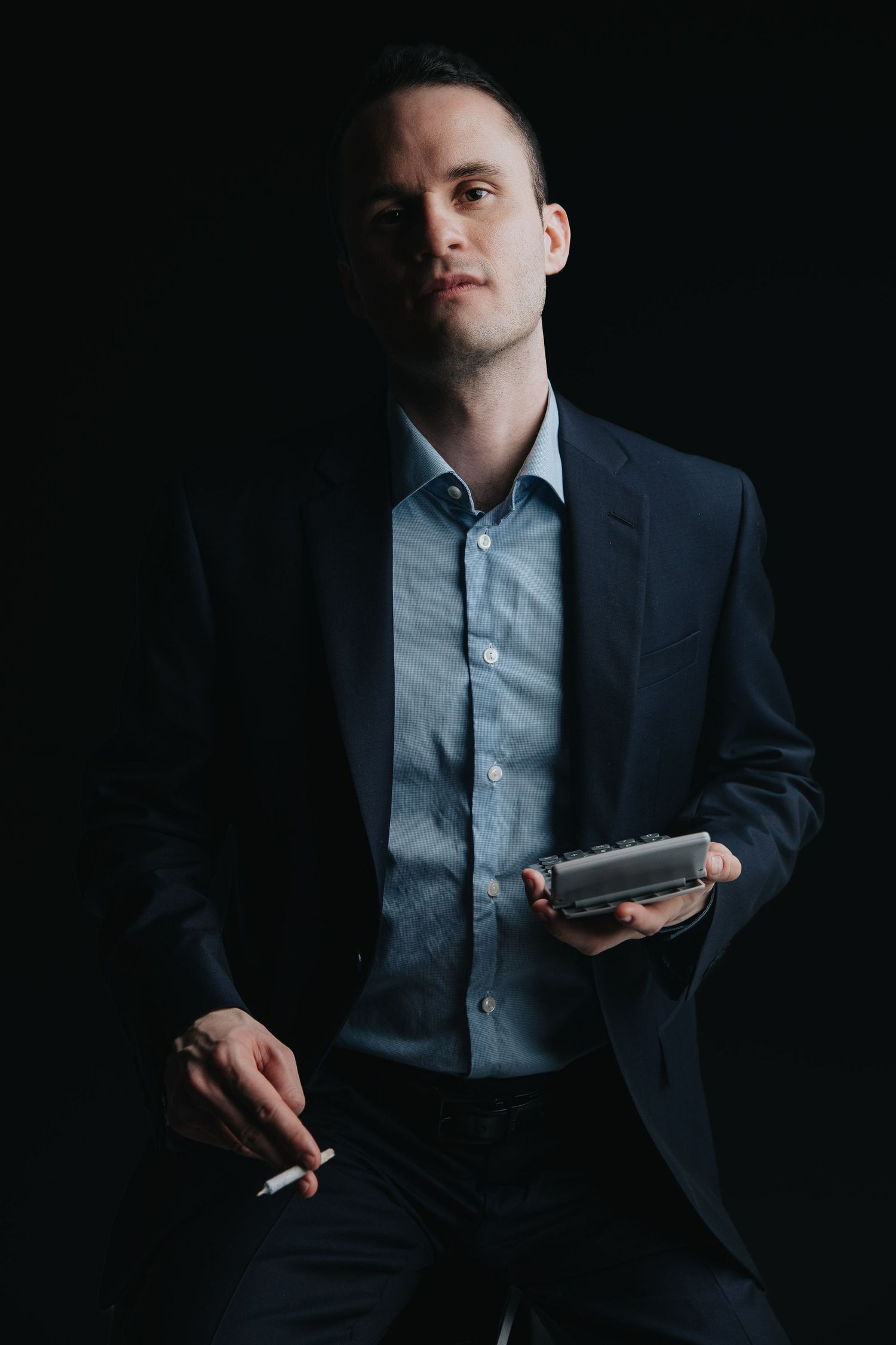 Moody business portraits in dark setting with person in navy suit and light blue shirt.