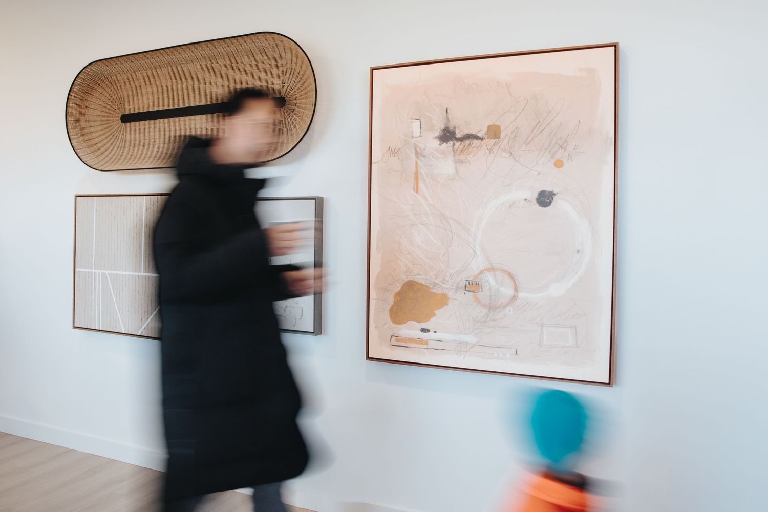 Motion blur of people walking through modern art gallery with minimalist white walls.