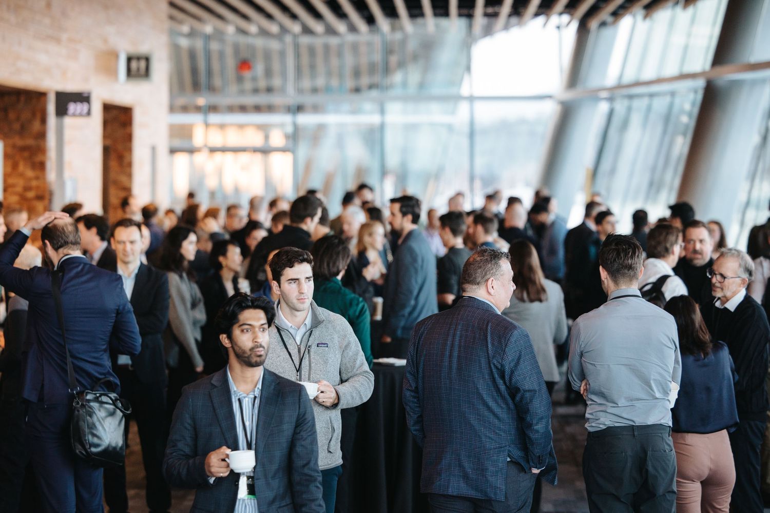 Business professionals networking and mingling at a crowded corporate event in a modern office space.