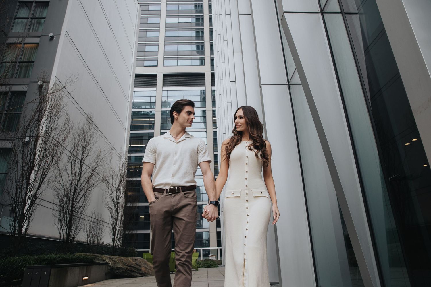 Couple strolling through a contemporary urban space with angular white architecture.