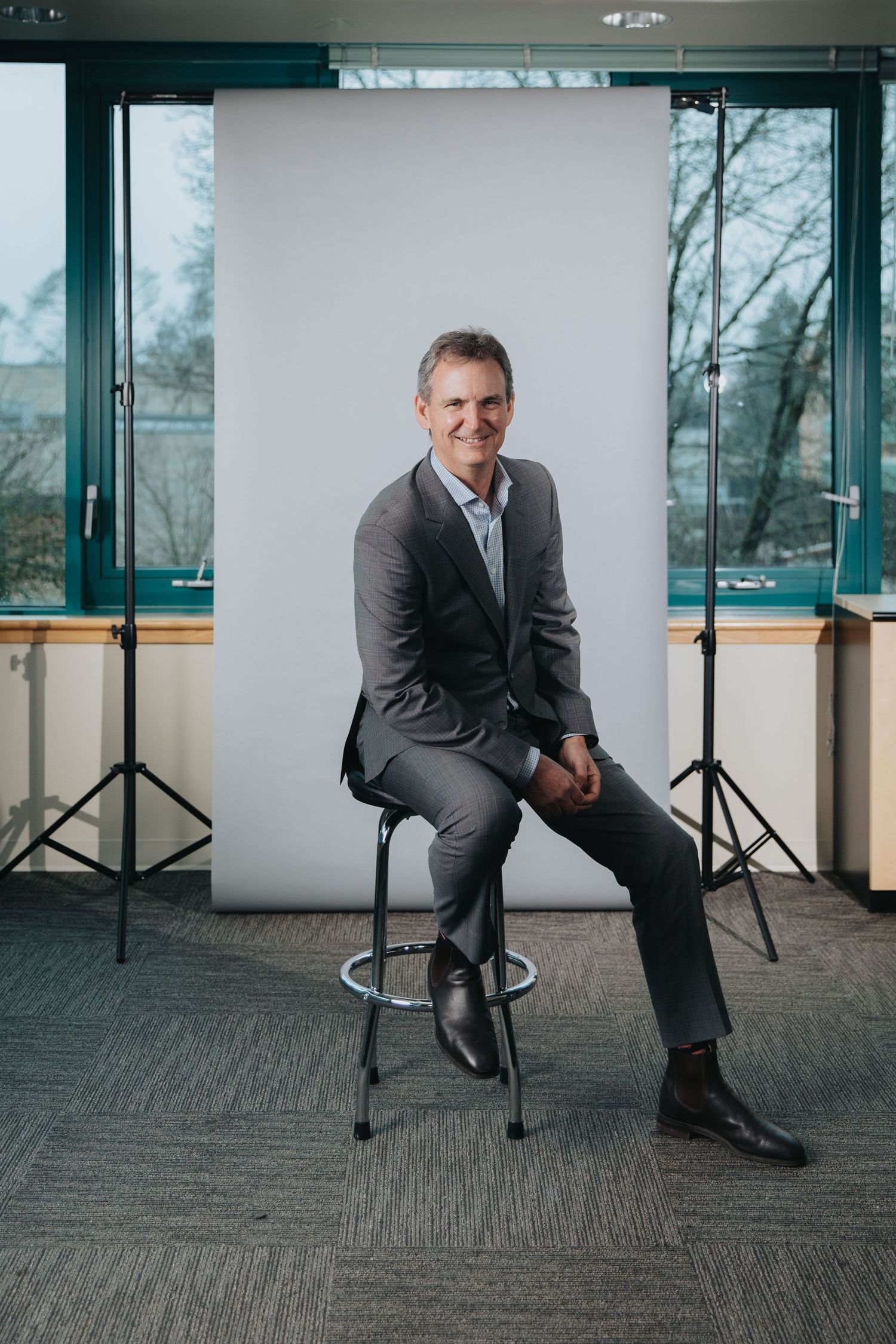 Professional seated on office chair in business attire against white background.