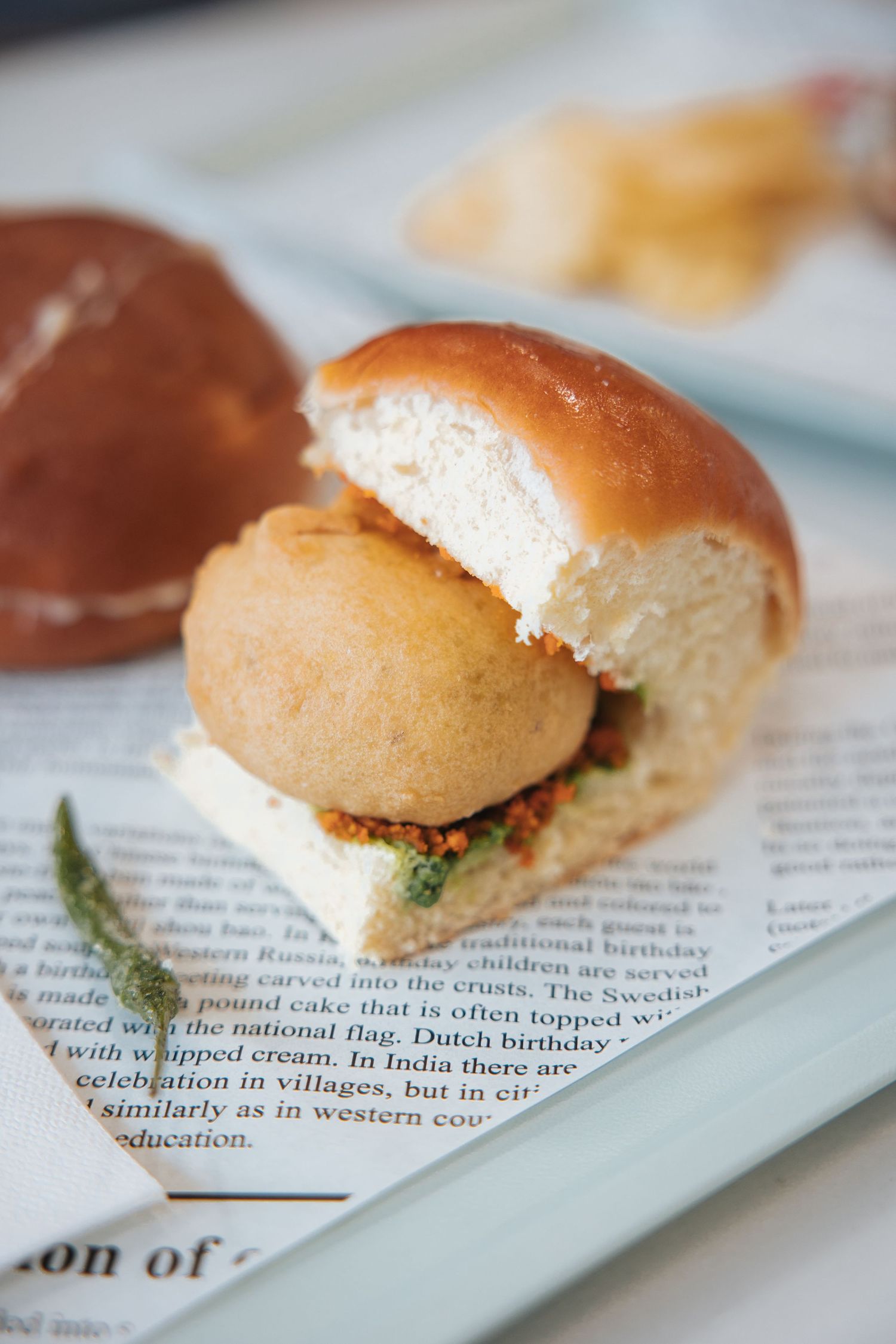 Close-up of small sandwiches on newspaper print with herbs and garnishes.