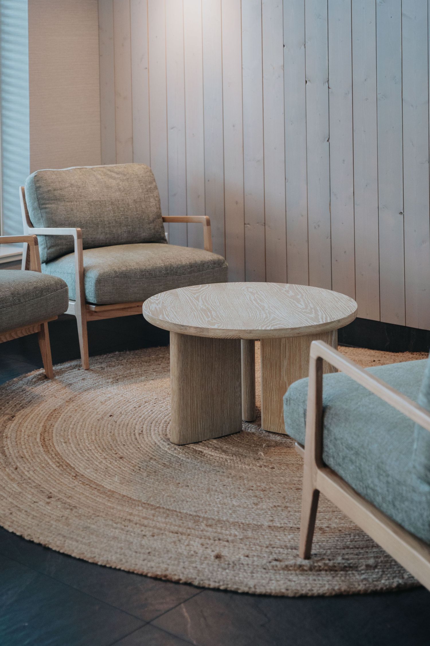 Modern minimalist seating area with round coffee table and jute rug.