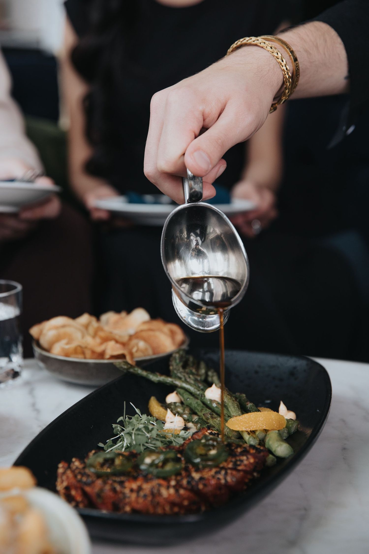 Elegant plated dishes being served at an upscale restaurant with dark and moody lighting.