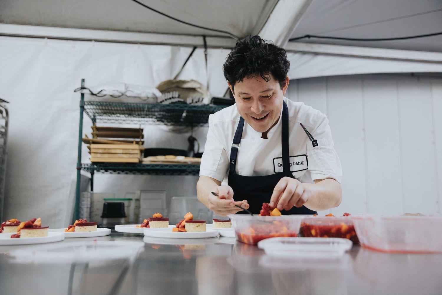 Chef working meticulously in commercial kitchen with prep stations visible.