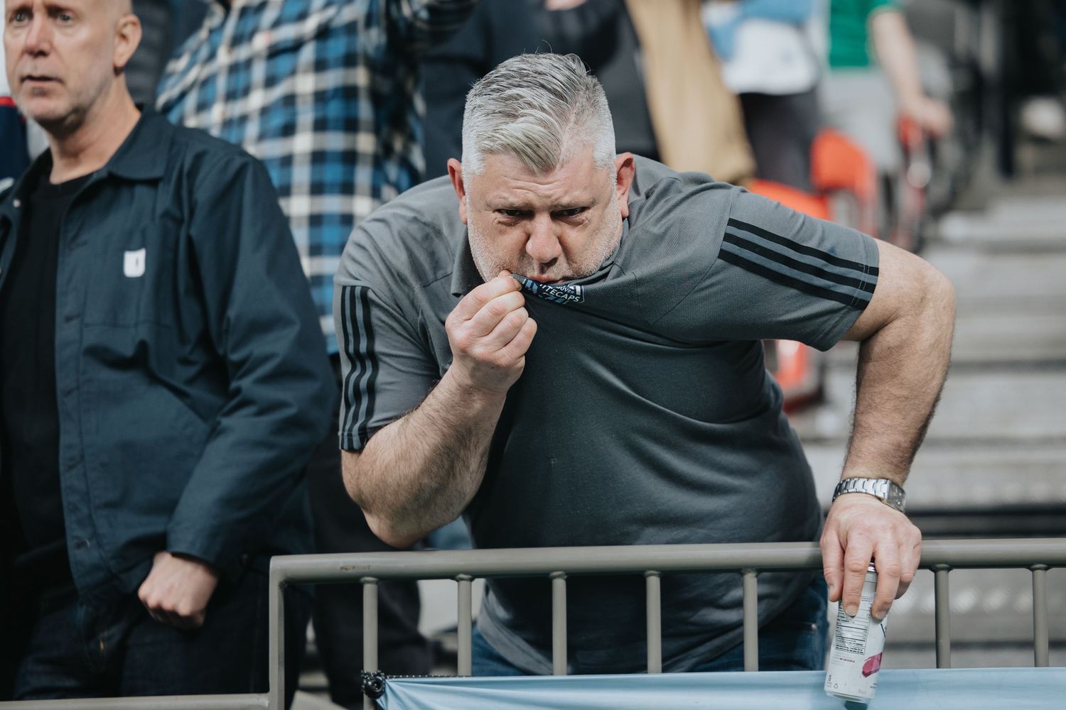 Spectators display intense reactions while watching a sporting event from the stands.