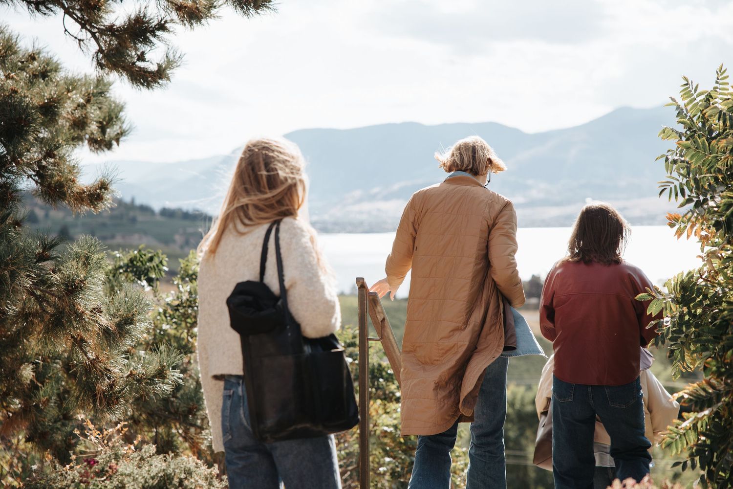 Silhouettes of people standing against a mountainous landscape during golden hour.