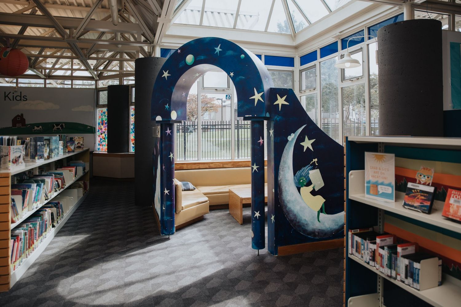 Library interior with themed decorative elements and bookshelves under a skylight.