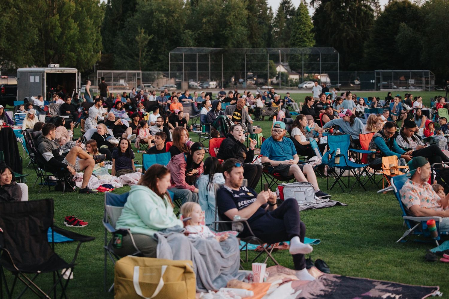 Large audience seated on lawn watching outdoor performance.