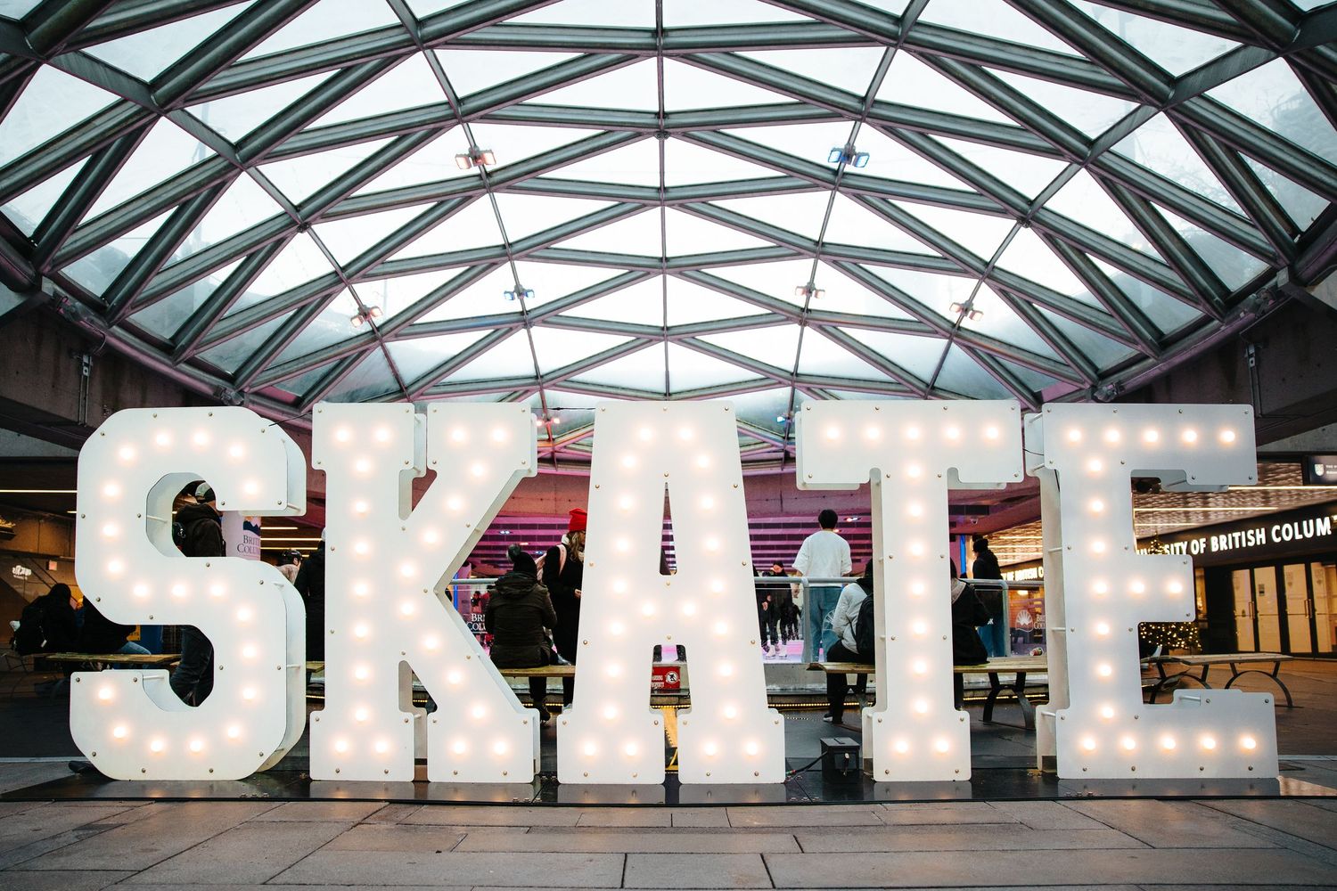 Modern glass dome architecture with illuminated SKATE signage.