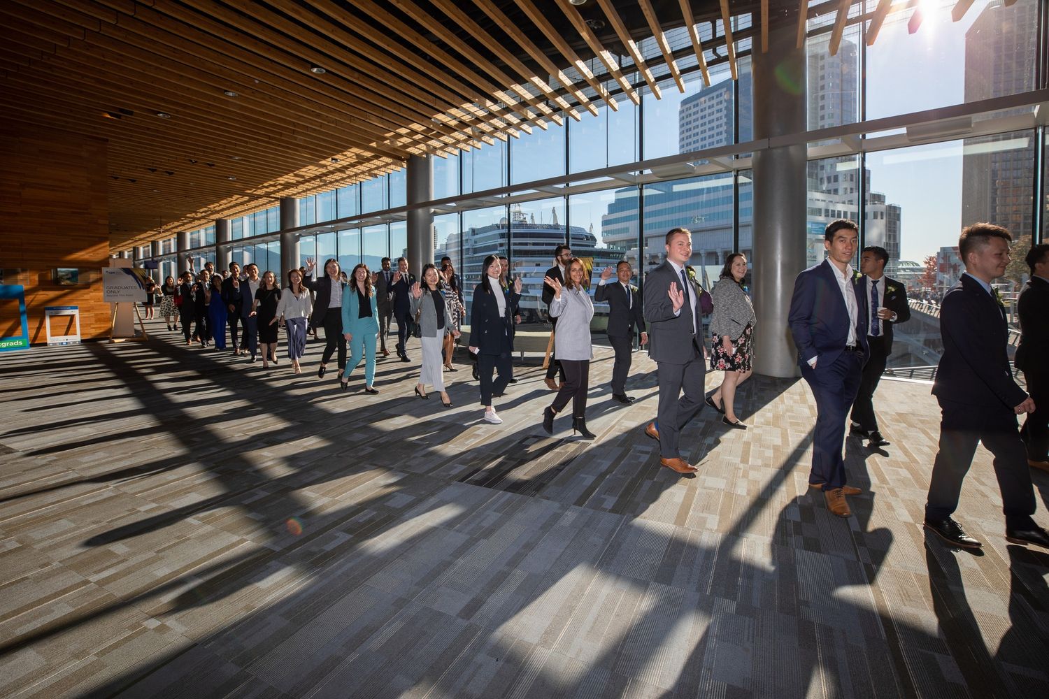 People walking through modern corridor with angled shadows and natural lighting.