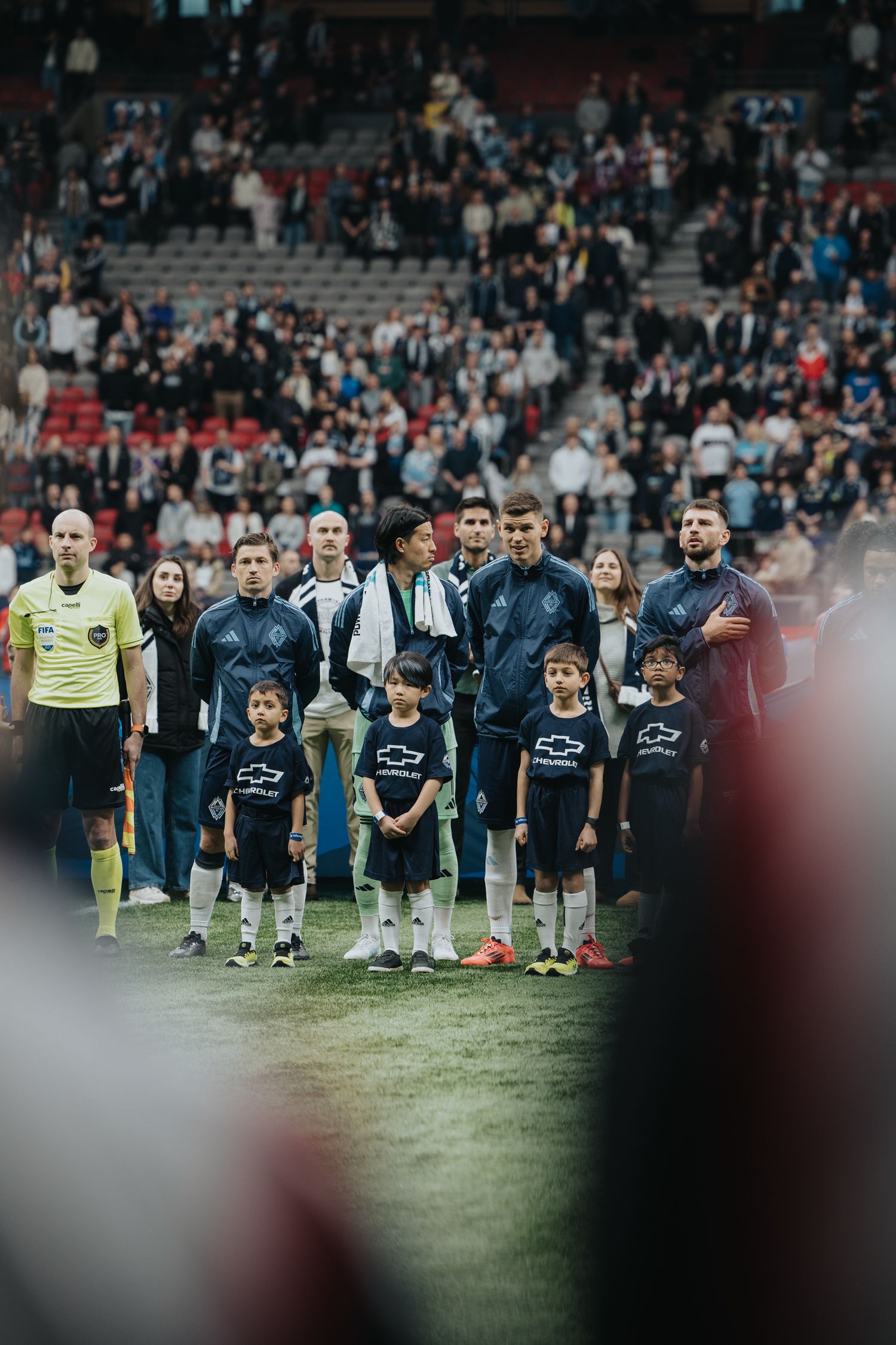 Soccer players and officials line up on the field before a match starts.