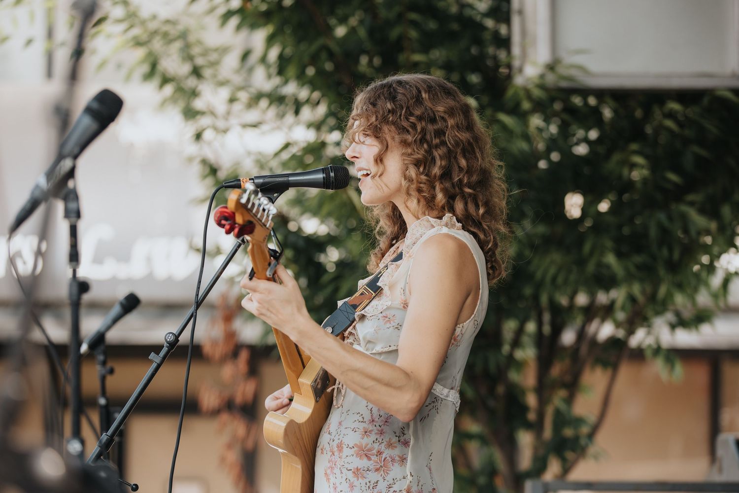 Musicians performing on outdoor stage with instruments during daytime event.