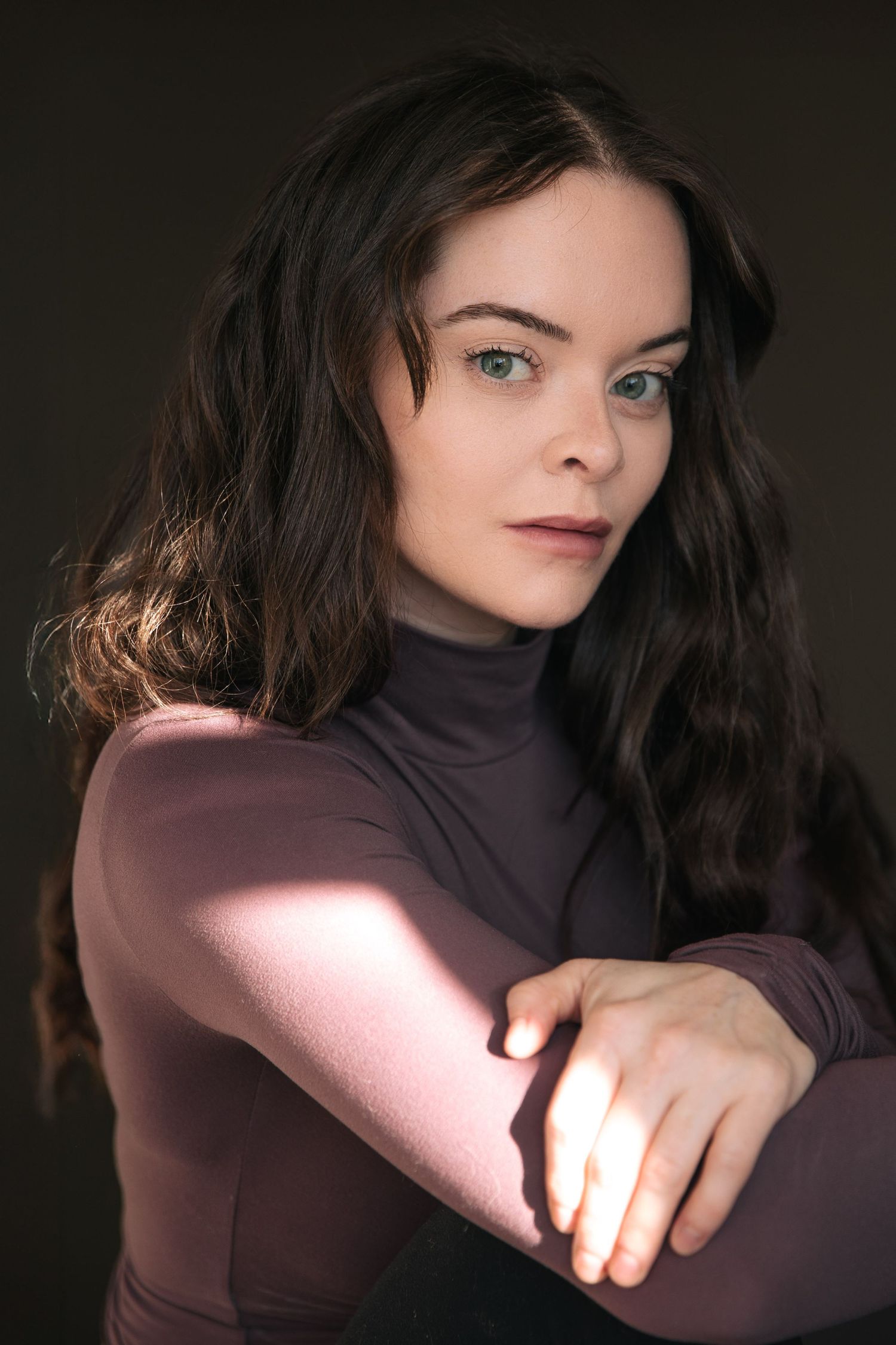 A series of moody portrait photographs showing a person in a dark turtleneck against a black background.