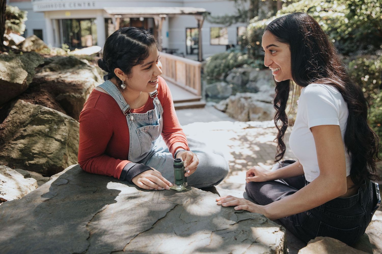 People sitting outdoors on rocky surfaces engaged in activities.