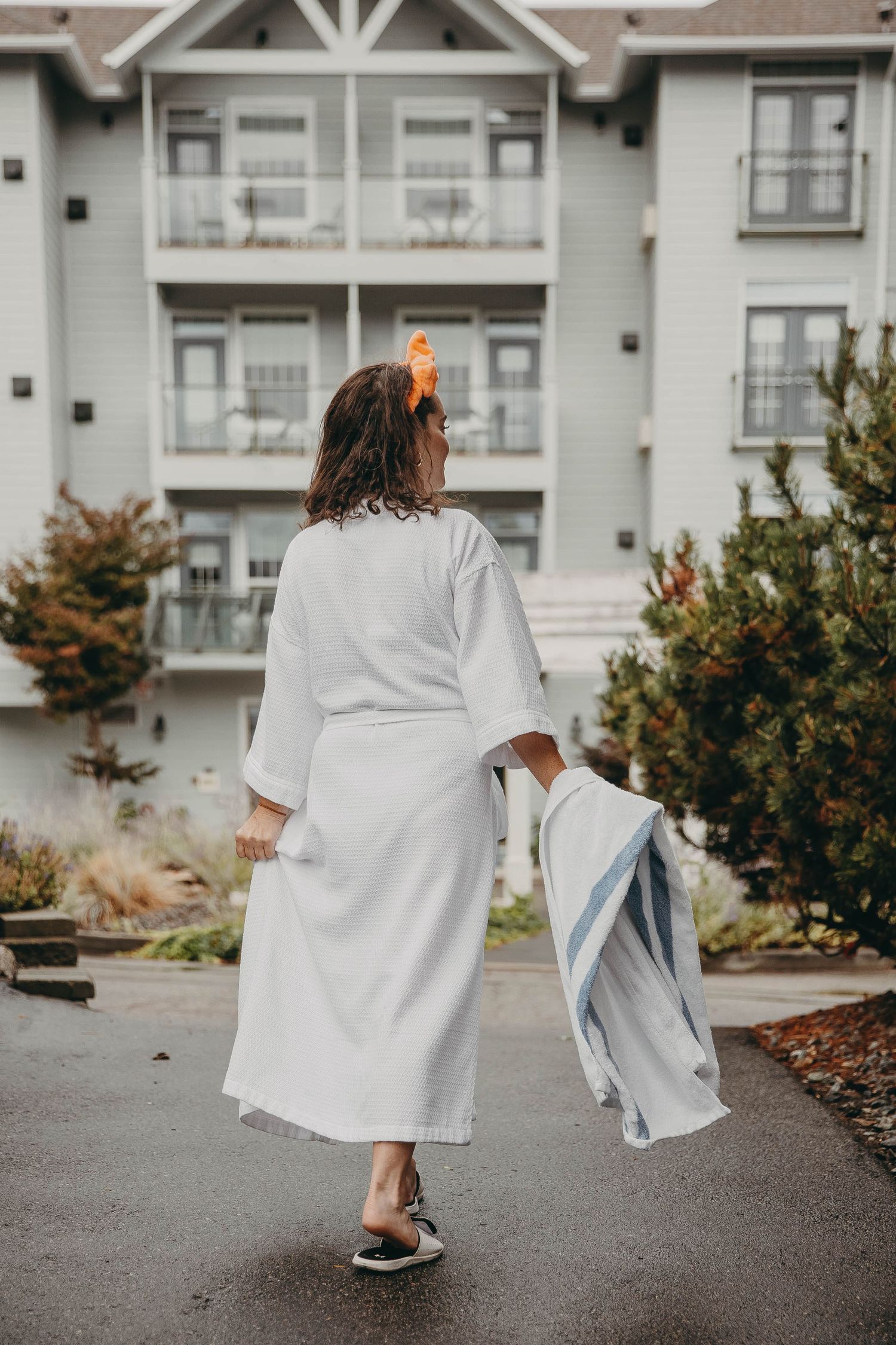 Person in white robe walking through apartment complex courtyard.