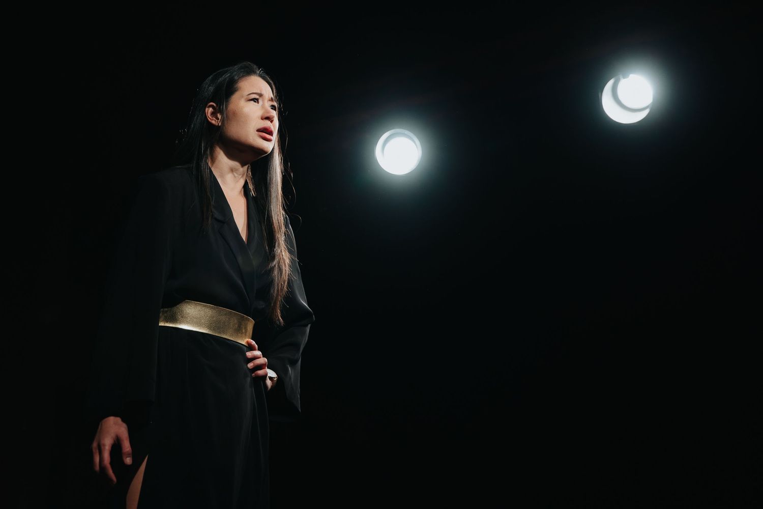 Professional speaker presenting at a business conference with dramatic lighting and modern architecture.