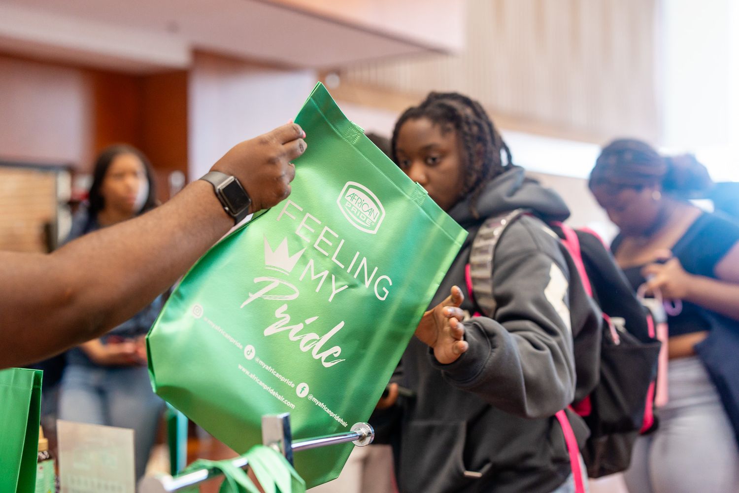 Students receive green tote bags reading Feeling My Pride at a college orientation event.