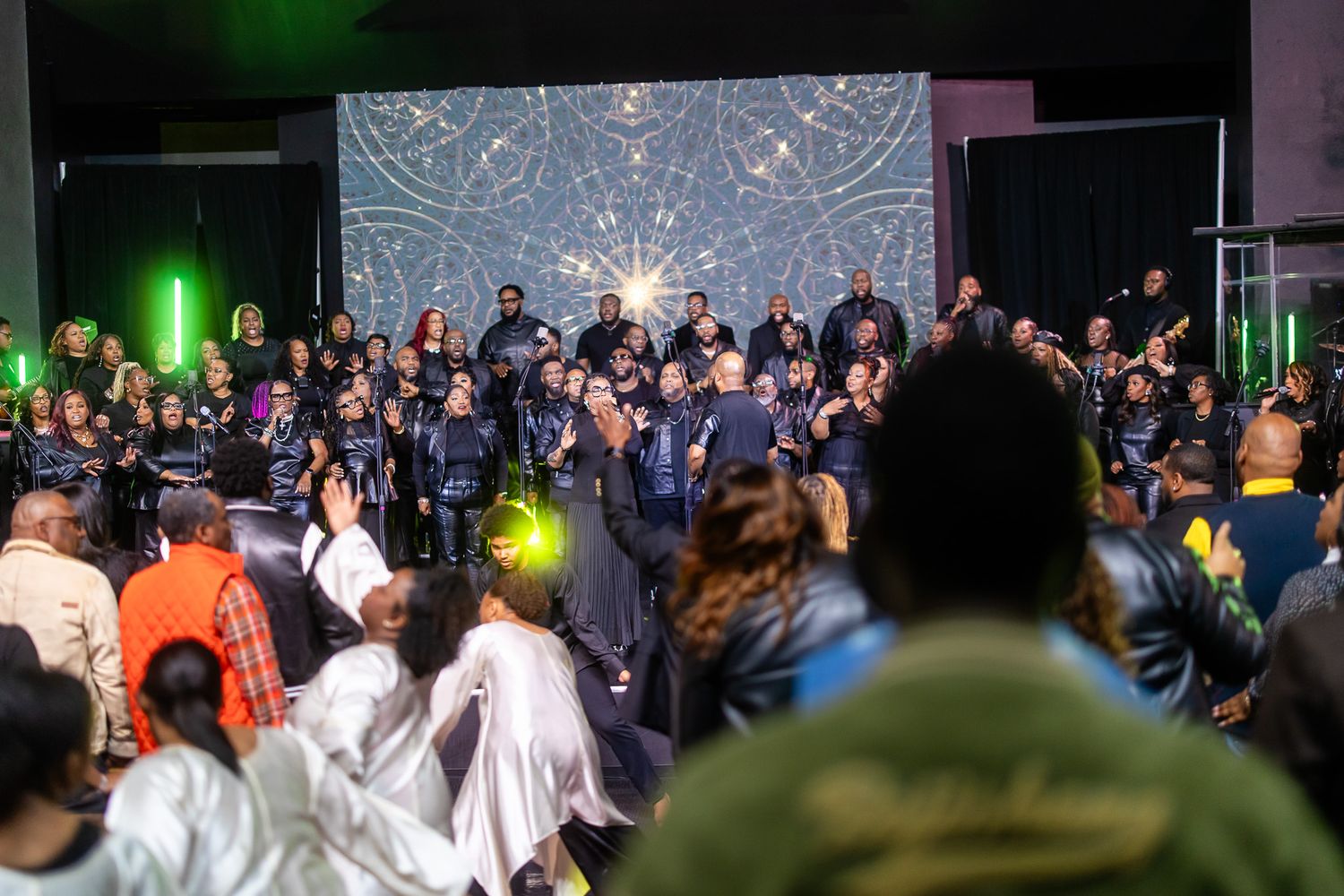 Large audience gathered in dark venue with stage lighting and special effects.