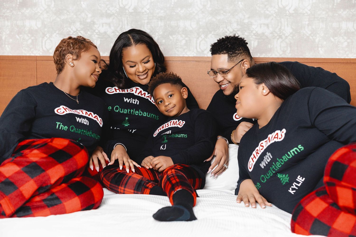 Friends huddled together under cozy red plaid blankets sharing warm smiles.