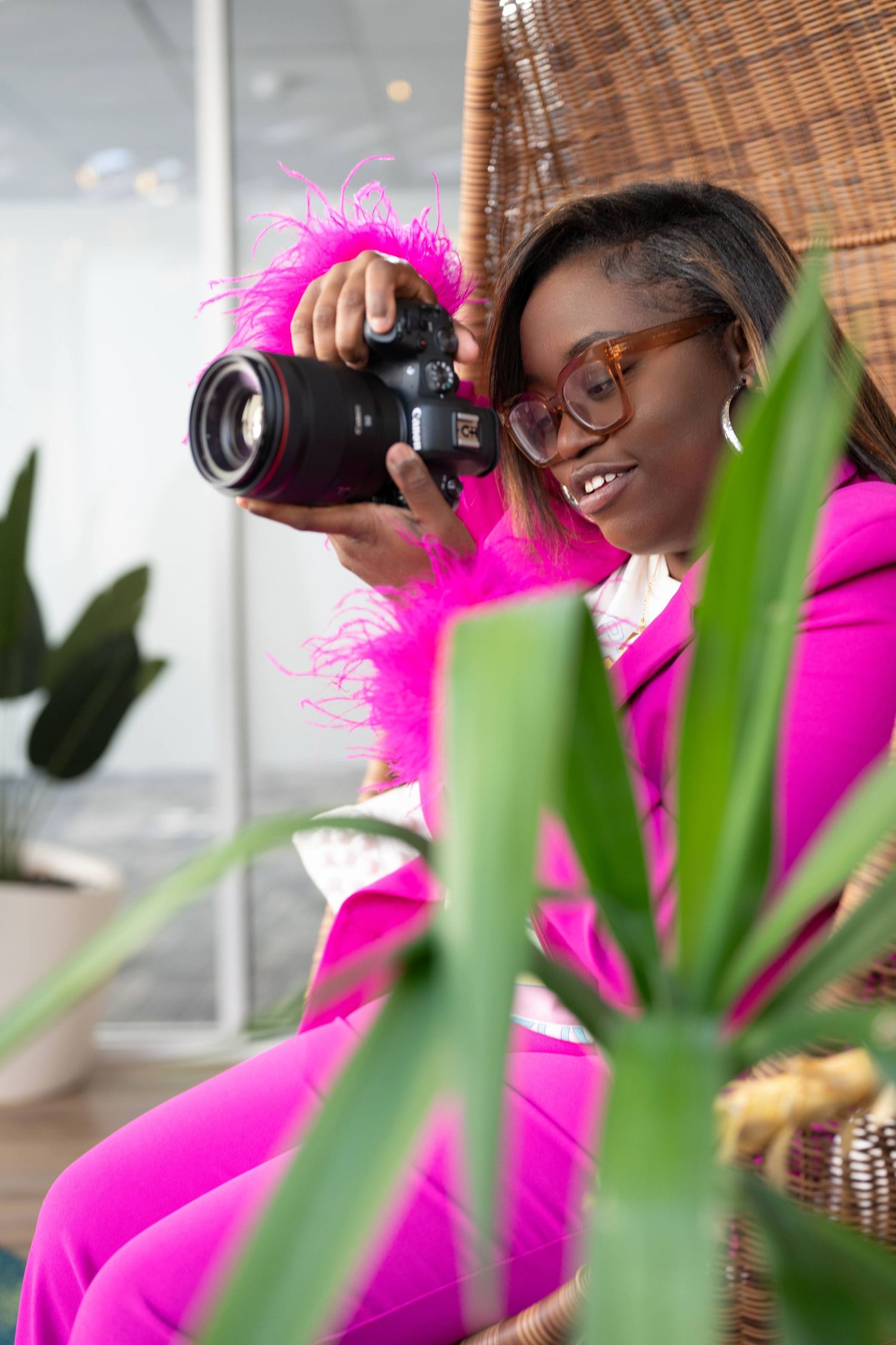 Photographer in bright pink outfit taking pictures among tropical plants.