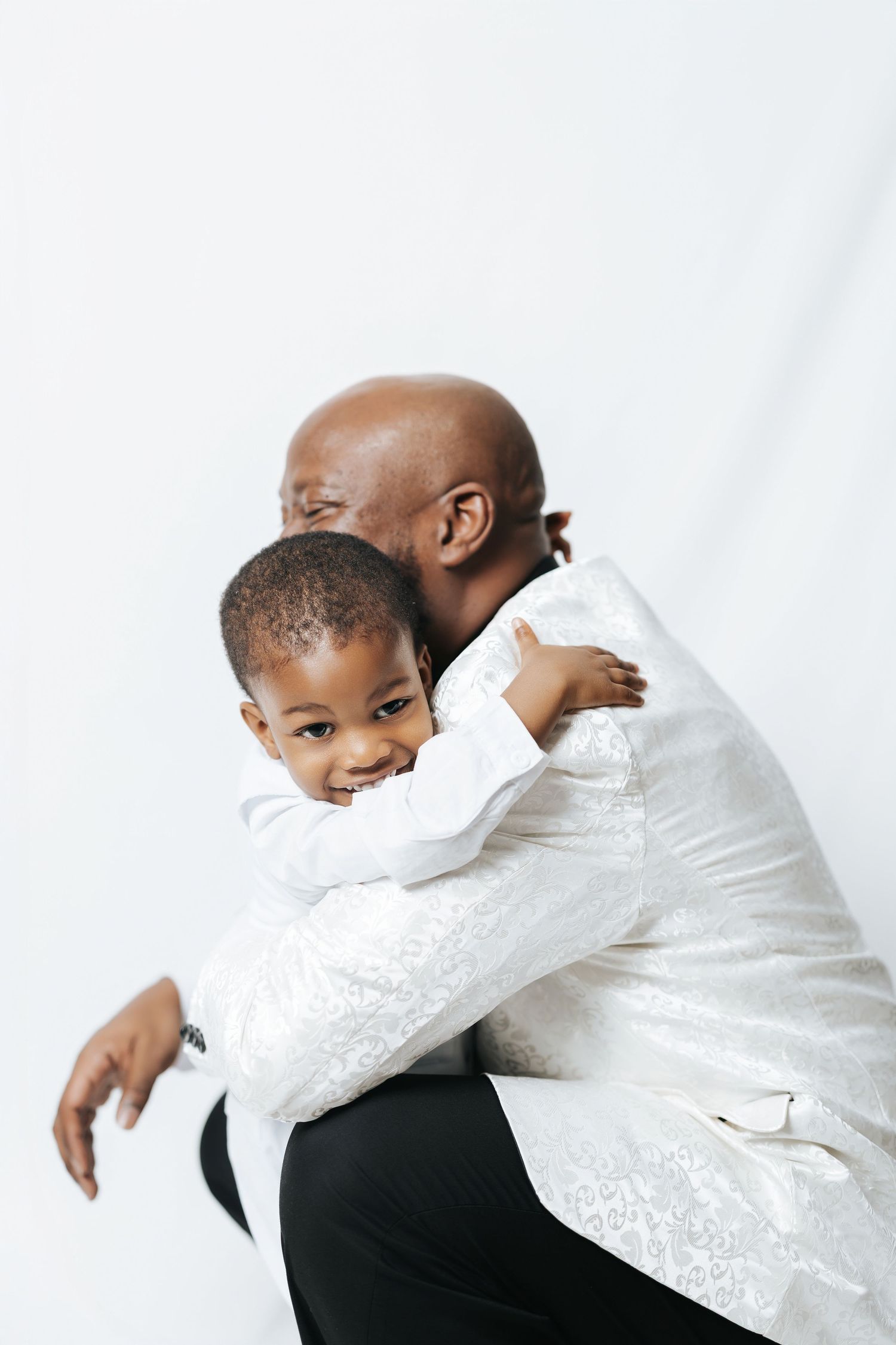 A heartwarming sequence shows a parent and child in white clothing sharing tender embraces against a white background.