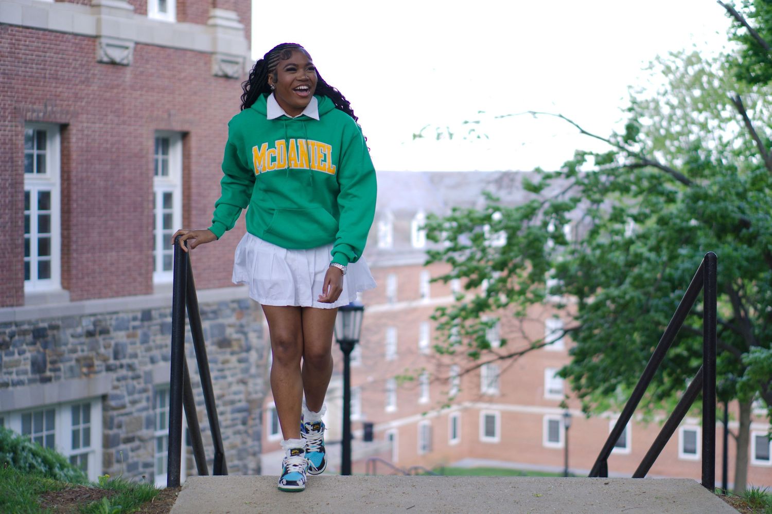 Student in McDaniel College sweatshirt walking up campus steps outdoors.