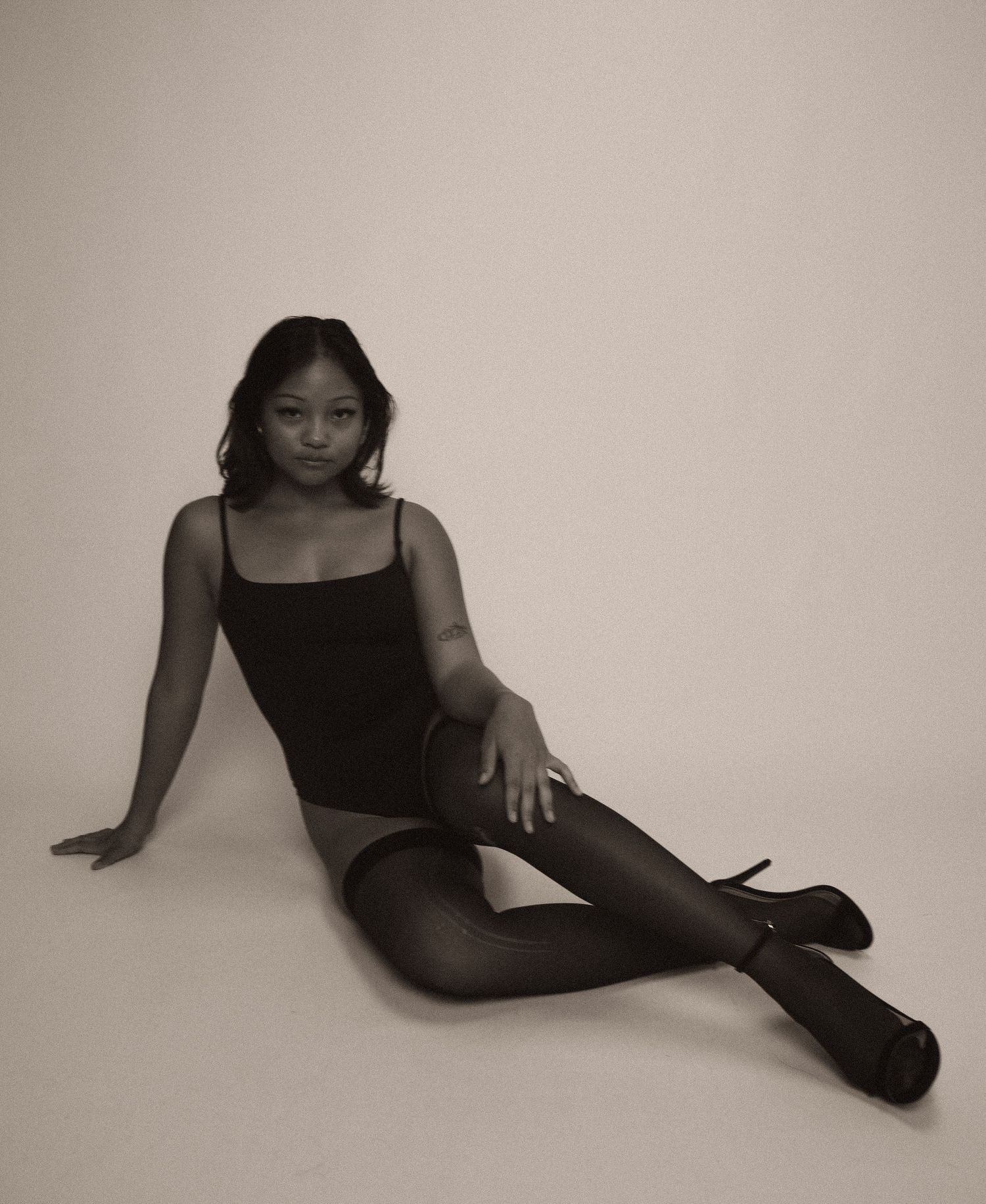 A figure in a black outfit poses gracefully in a series of artistic monochrome portrait shots against a neutral background.