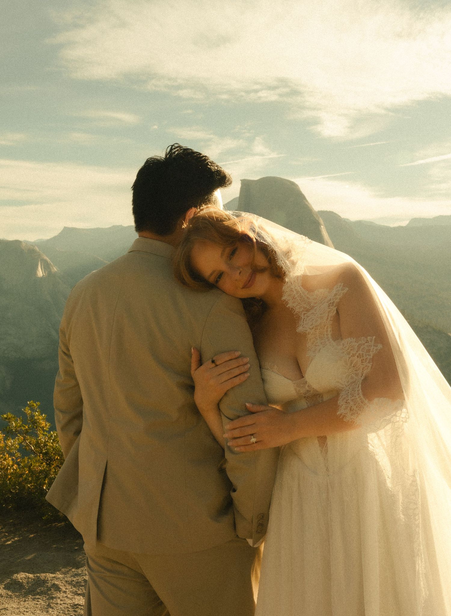 Bride and groom embracing at sunset with mountain vista backdrop at Yosemite wedding ceremony.