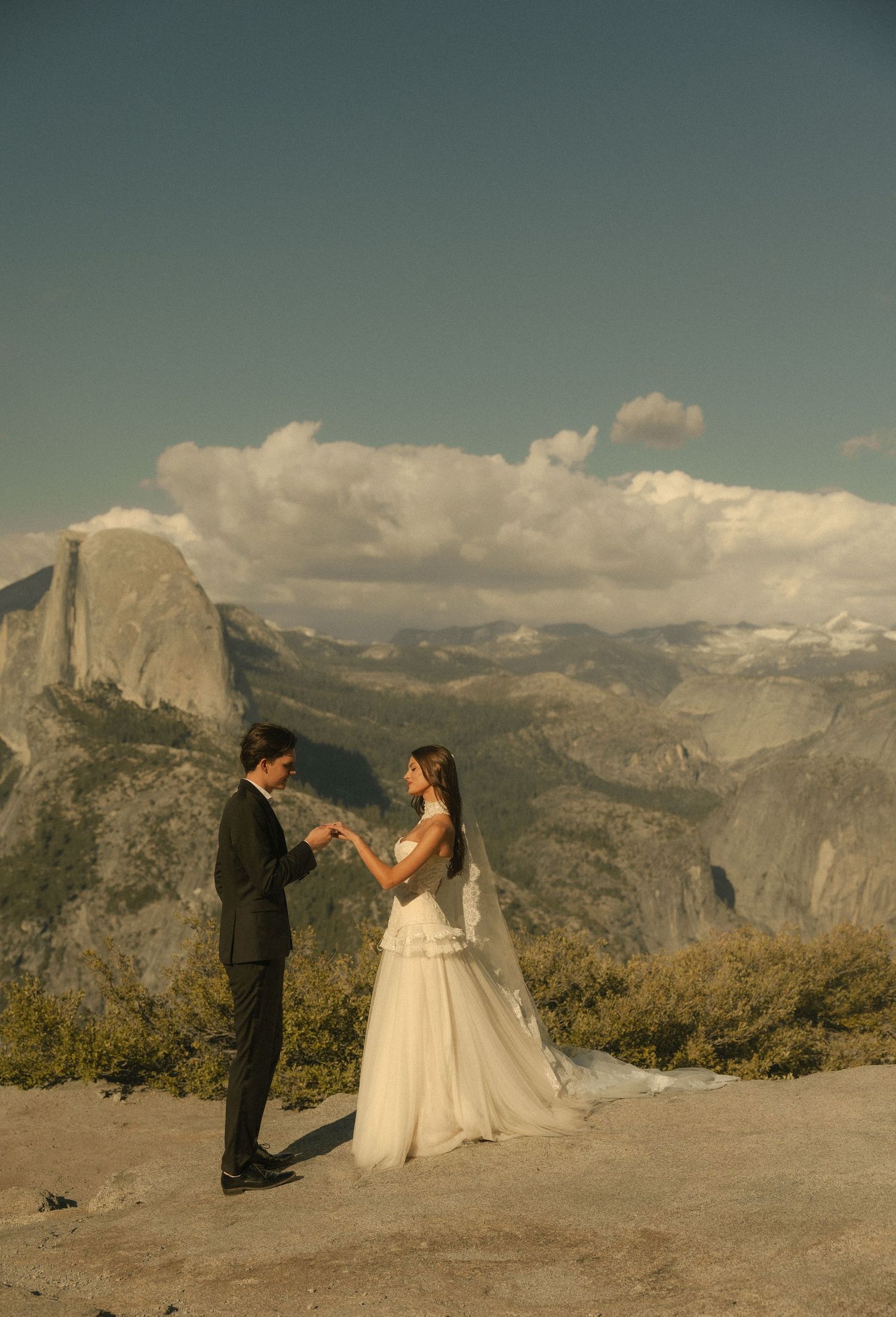 Couple exchanging vows at Glacier Point, Yosemite, with Half Dome and mountain views backdrop.