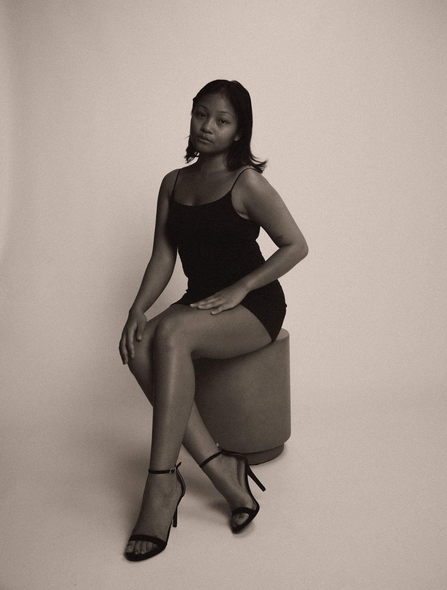 A series of black and white artistic portrait photos showing a figure in a black dress posing against a light background.
