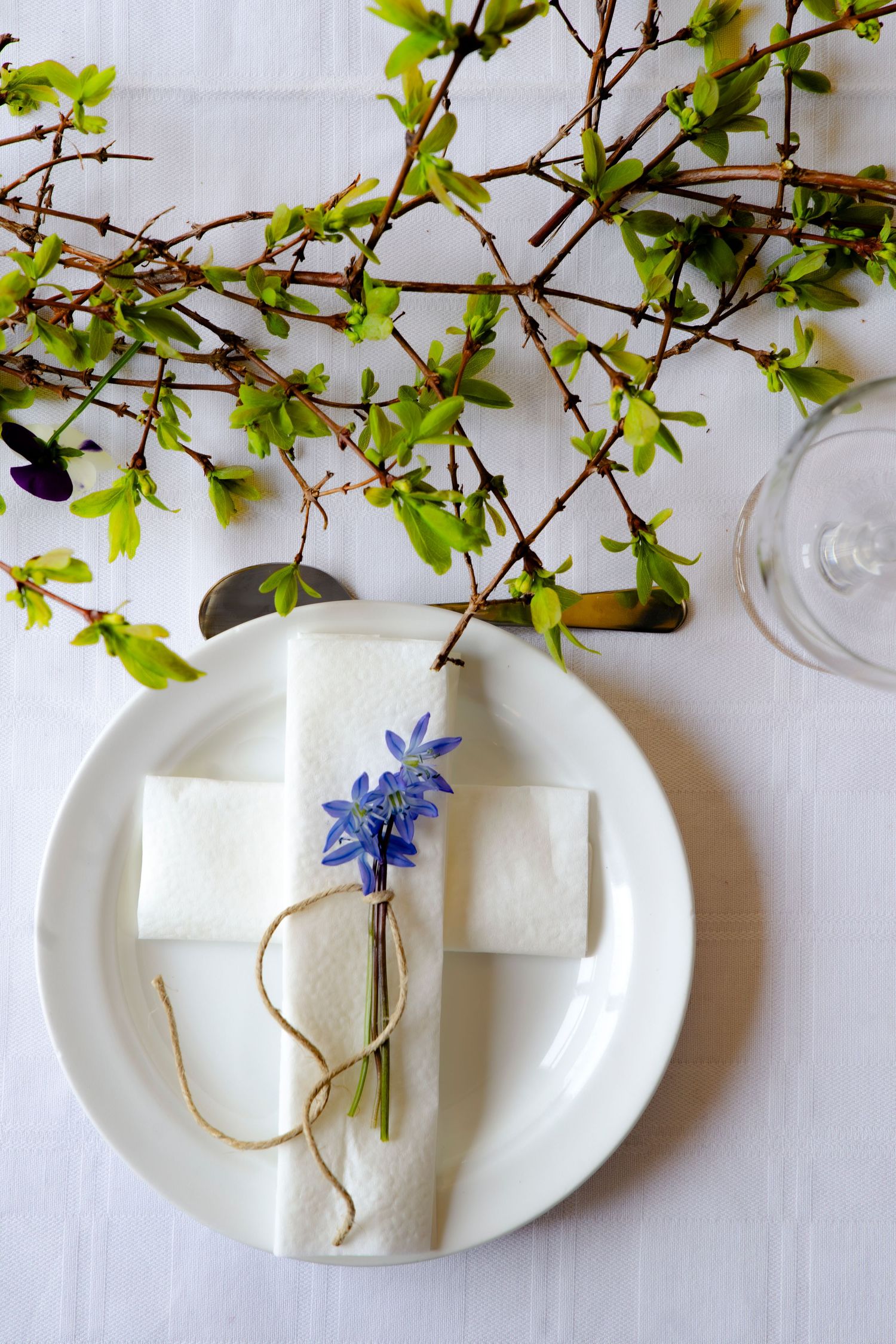 Dukat bord med vita tallrikar och vårblommor fotograferat i naturligt ljus av dokumentär fotograf i Norra Bohuslän.