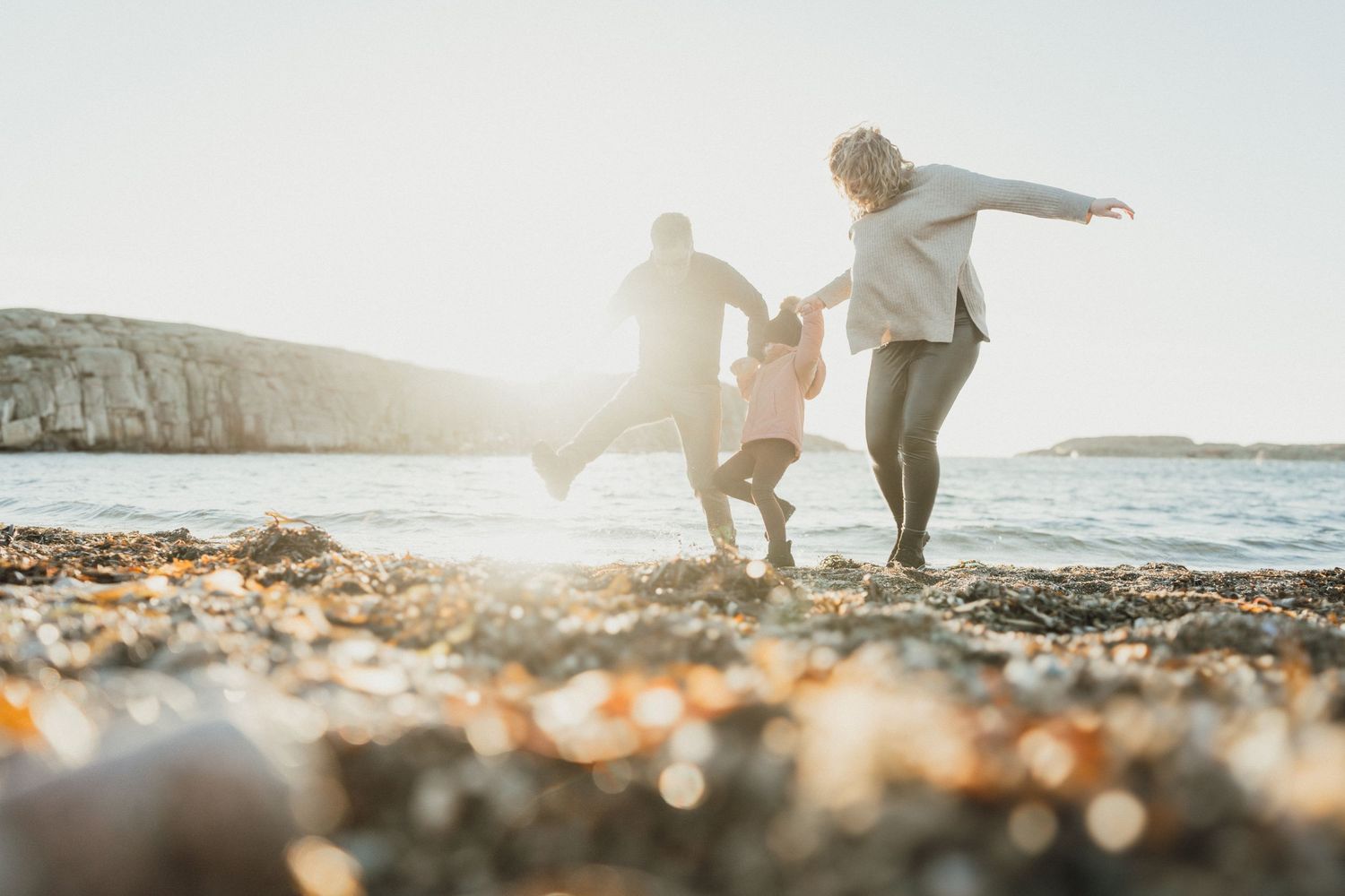 Föräldrar och barn leker tillsammans på stranden under dokumentär familjefotografering.