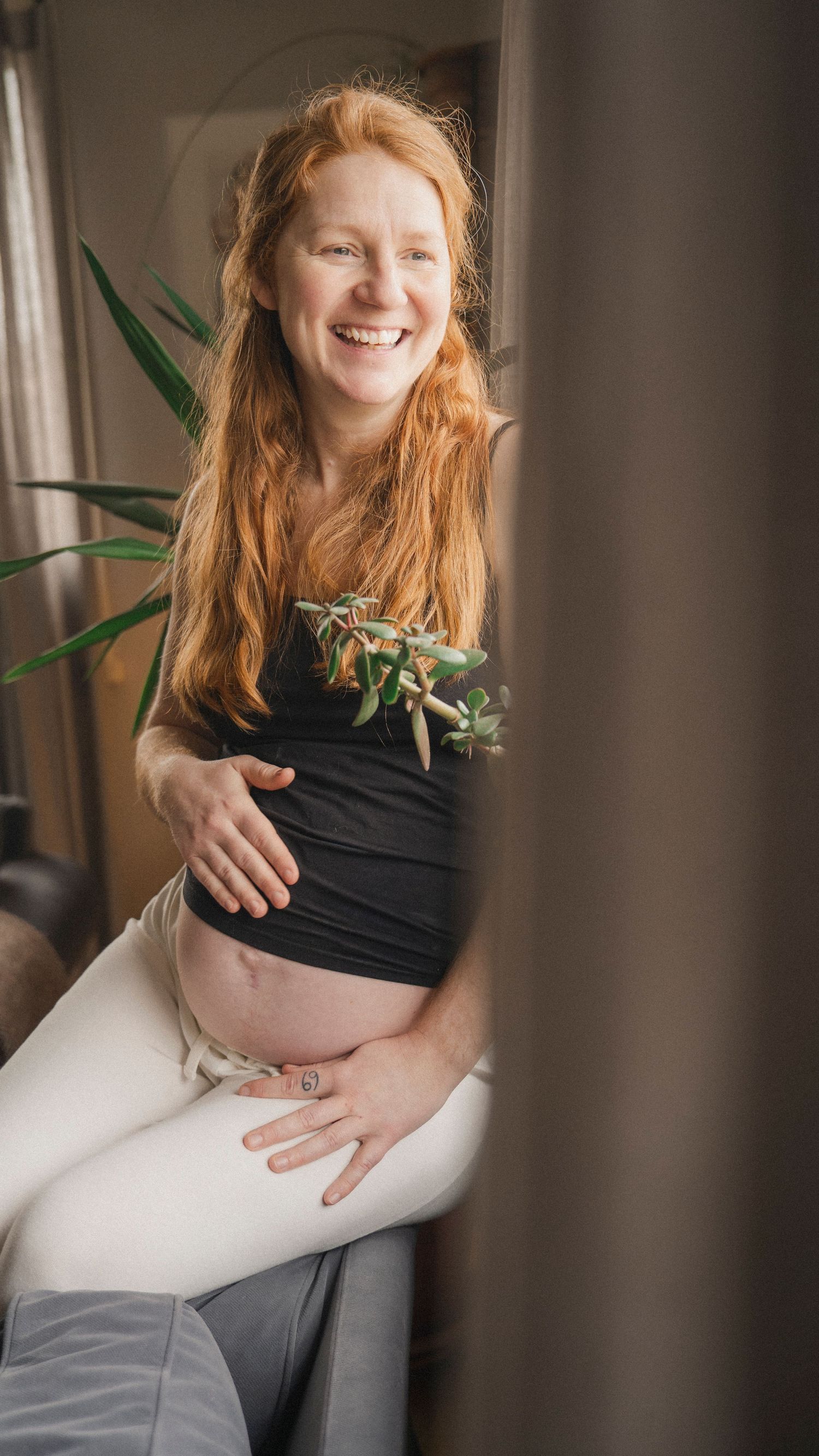 Gravid kvinna i mjukt morgonljus under en naturlig och dokumentär gravidfotografering hemma