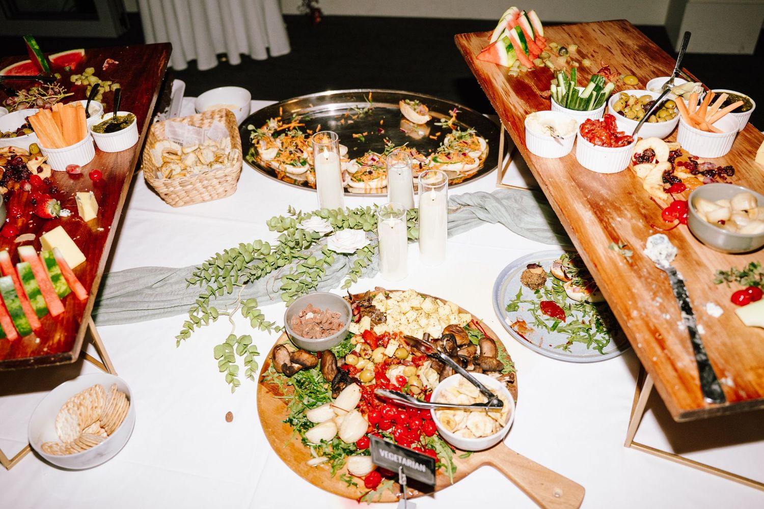 Elegant wedding reception grazing table with cheese boards and gourmet appetizers.