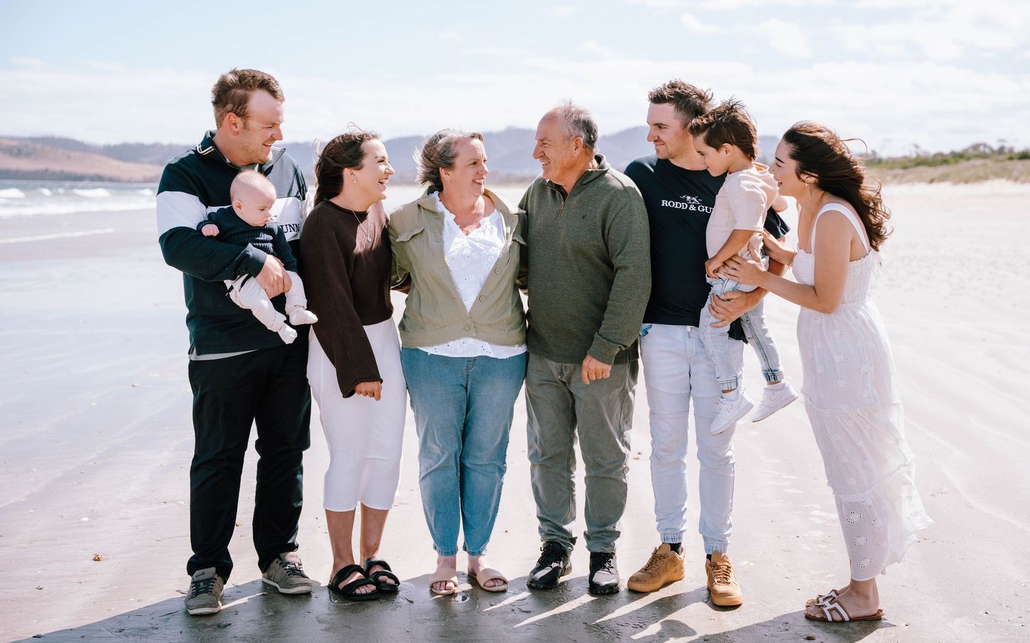 A group of people walking together on a beach wearing casual clothing in a candid moment.