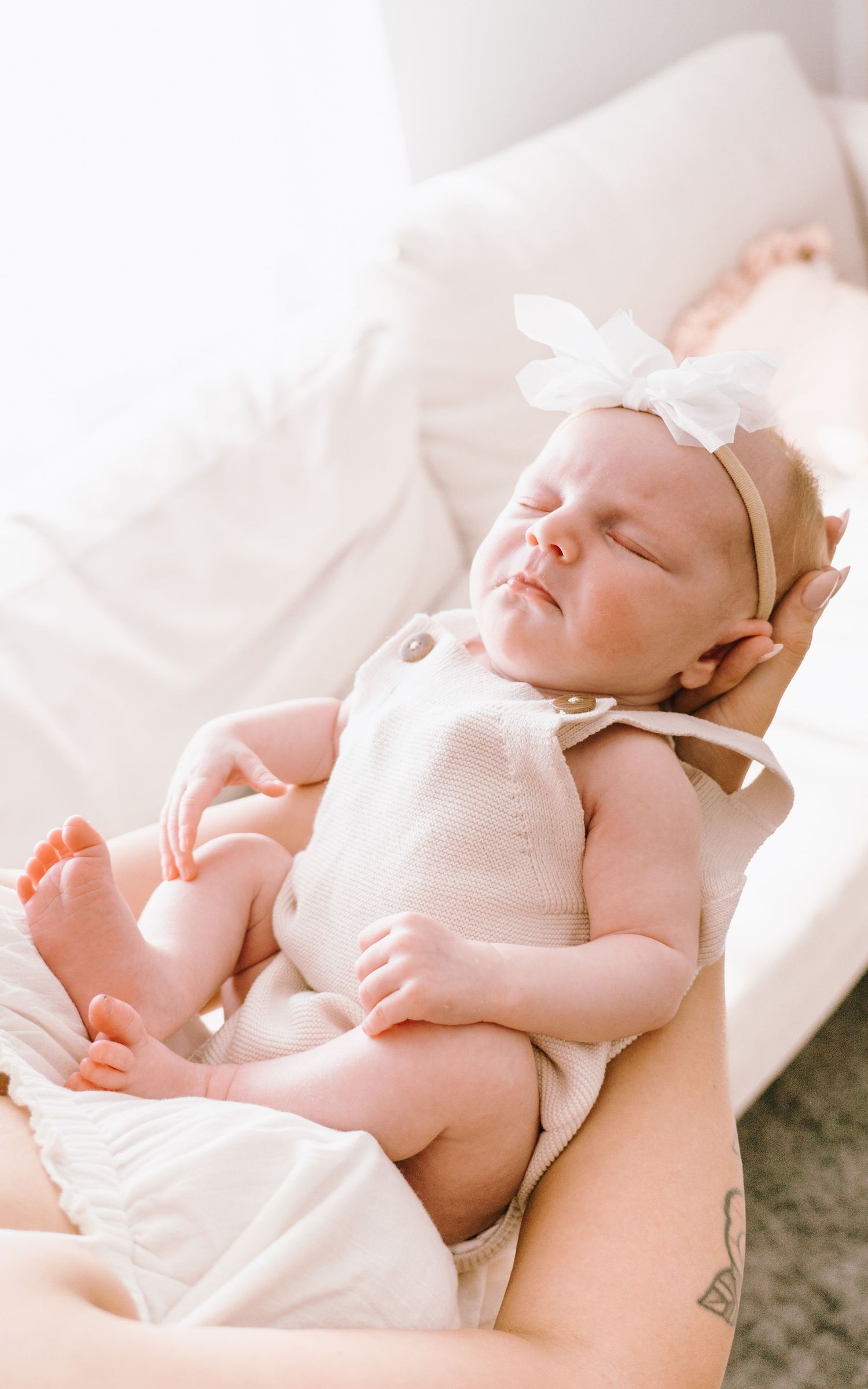 A series of tender moments showing a sleeping newborn baby in white clothing against soft white bedding.