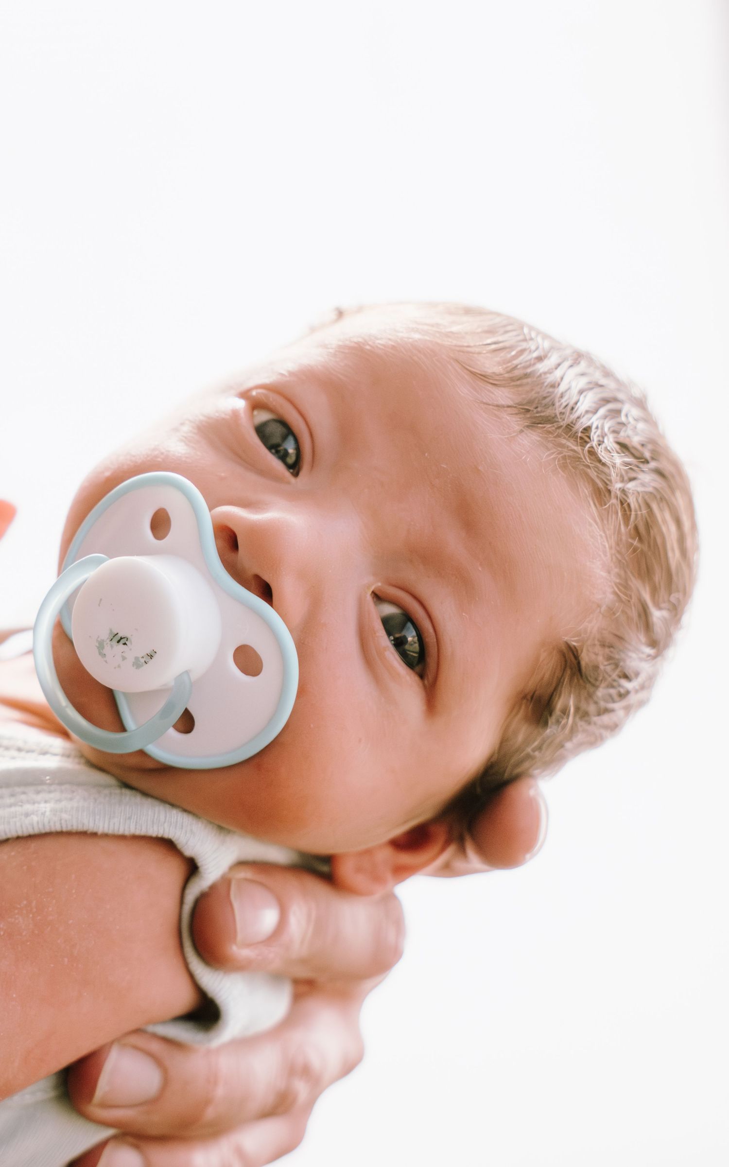 Baby with blue pacifier in mouth shown from different angles in close up shots.