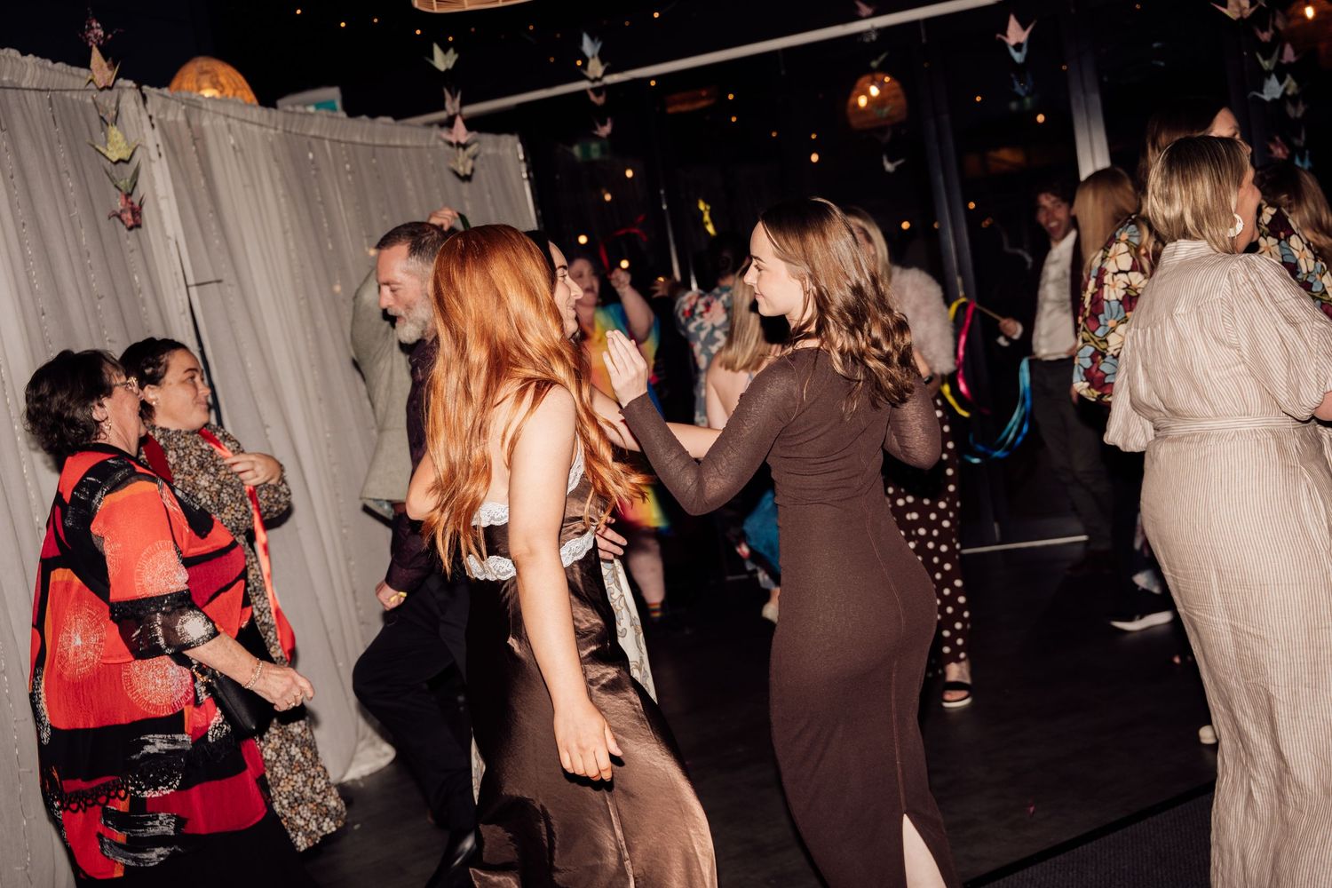 People dancing at a lively indoor party with colorful decorations and ambient lighting.