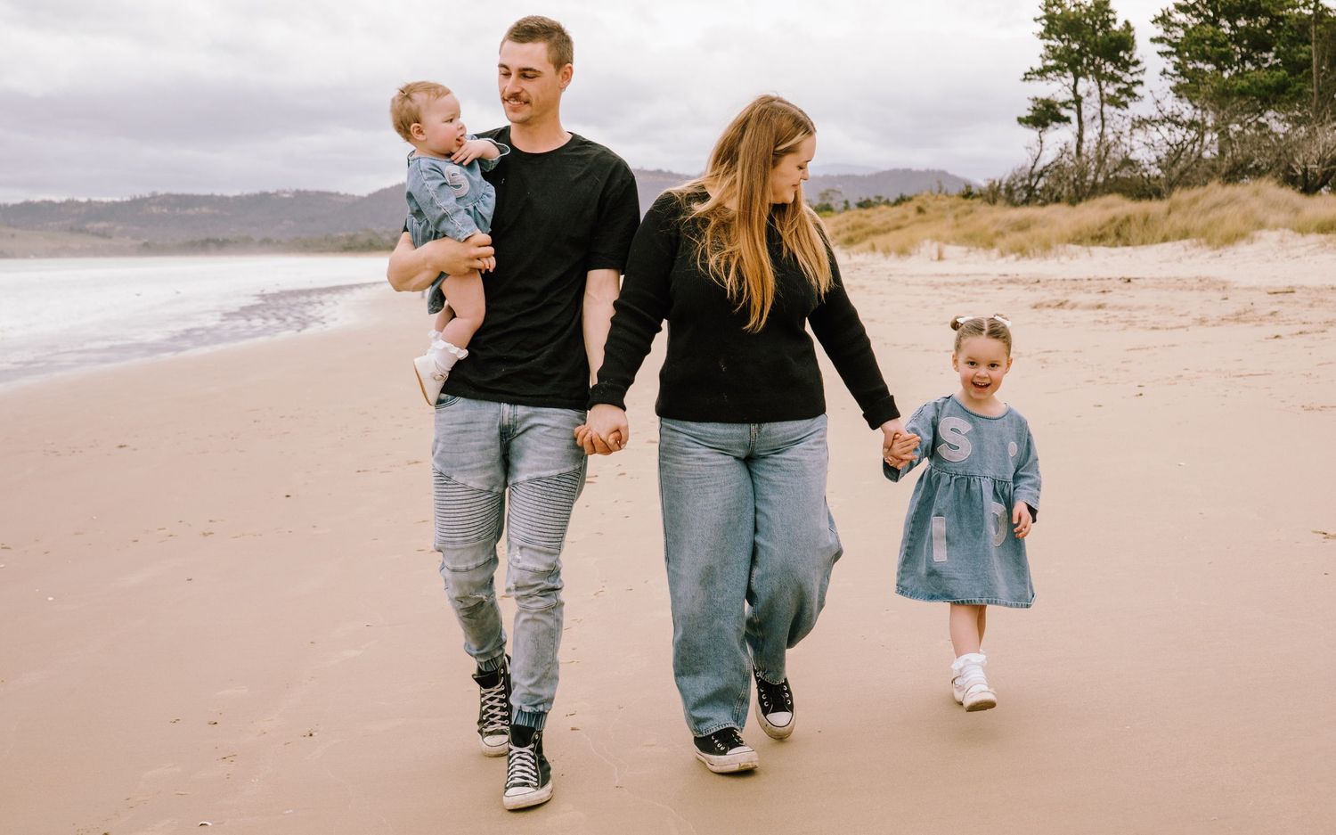 Family walking together along a scenic beach shoreline.