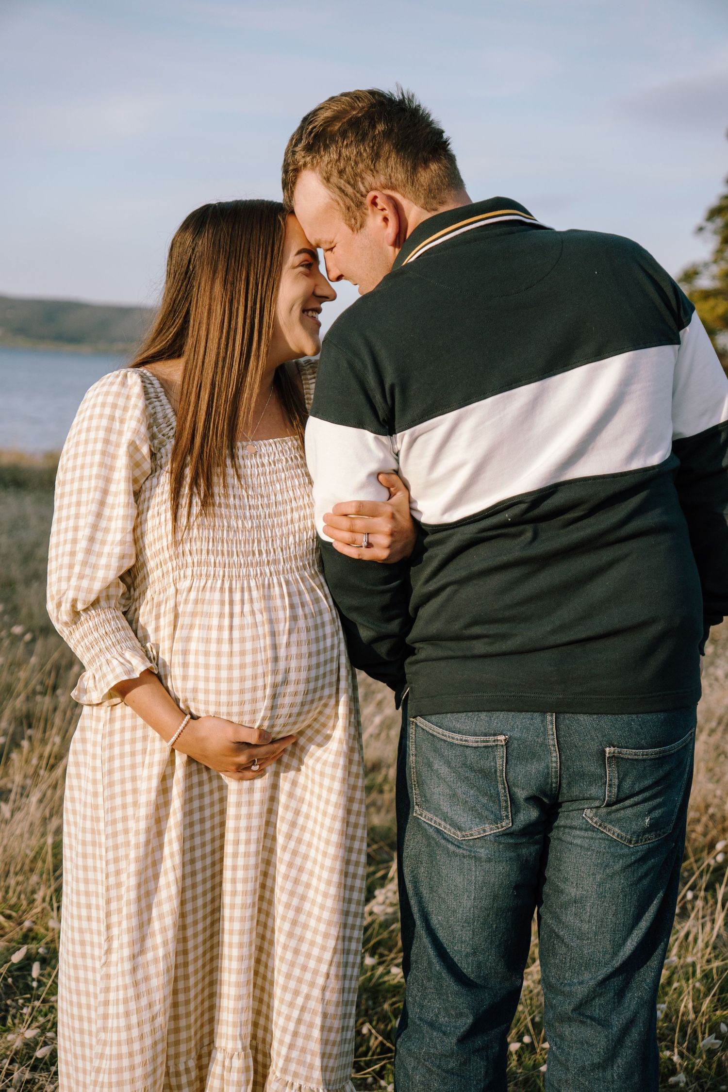A romantic couple embraces in a series of candid photos taken outdoors in golden light against a natural landscape.