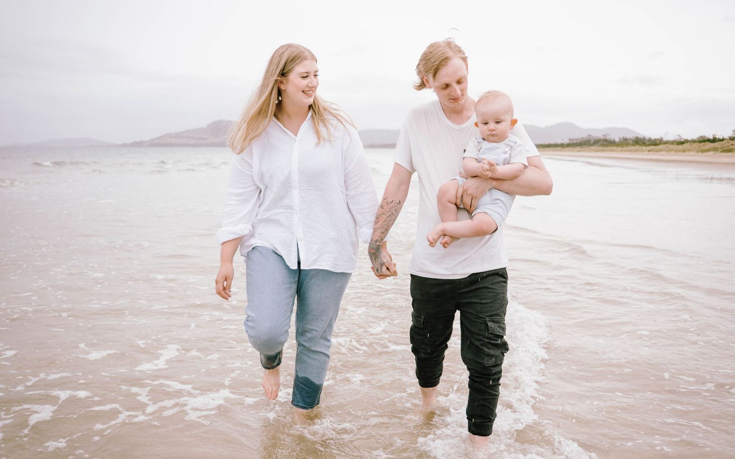 A family walking and playing together on a sandy beach during sunset, creating joyful moments by the ocean.