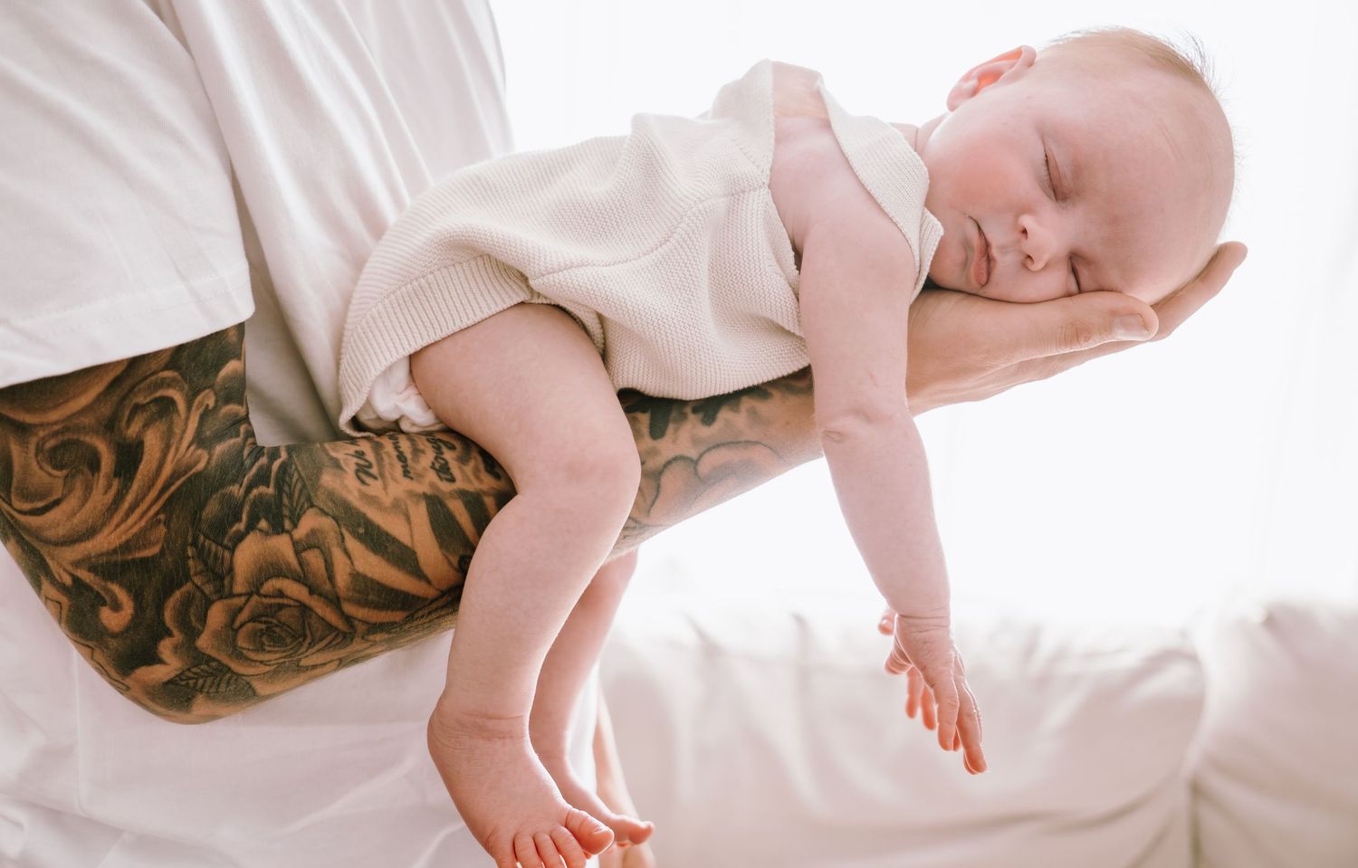 Sleeping infant on white bedding during lifestyle photoshoot.