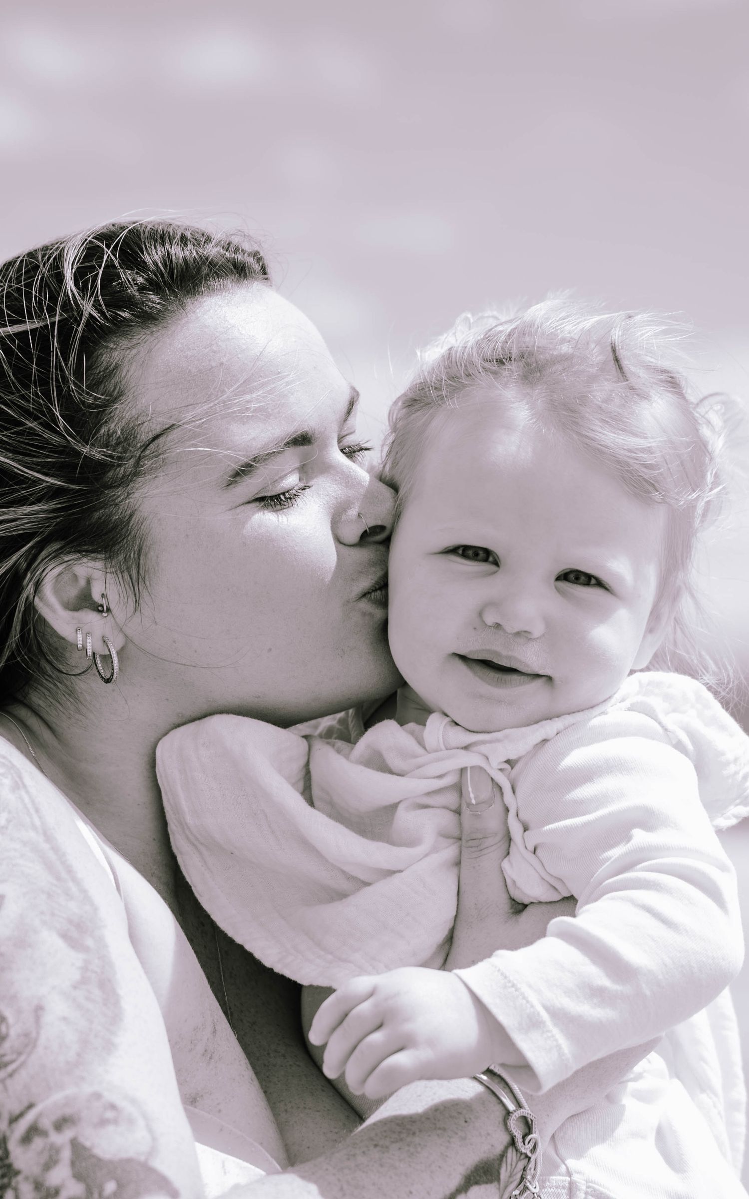 A tender black and white photo series showing loving moments between parent and child in soft lighting.