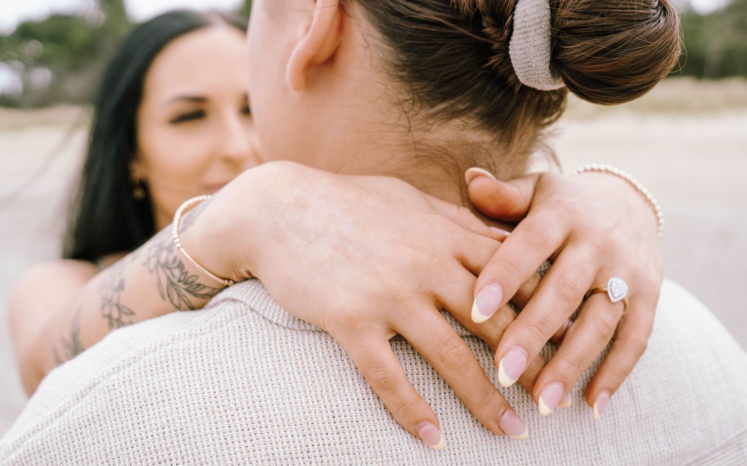 A close-up view of hands with wedding rings embracing in a romantic moment outdoors.
